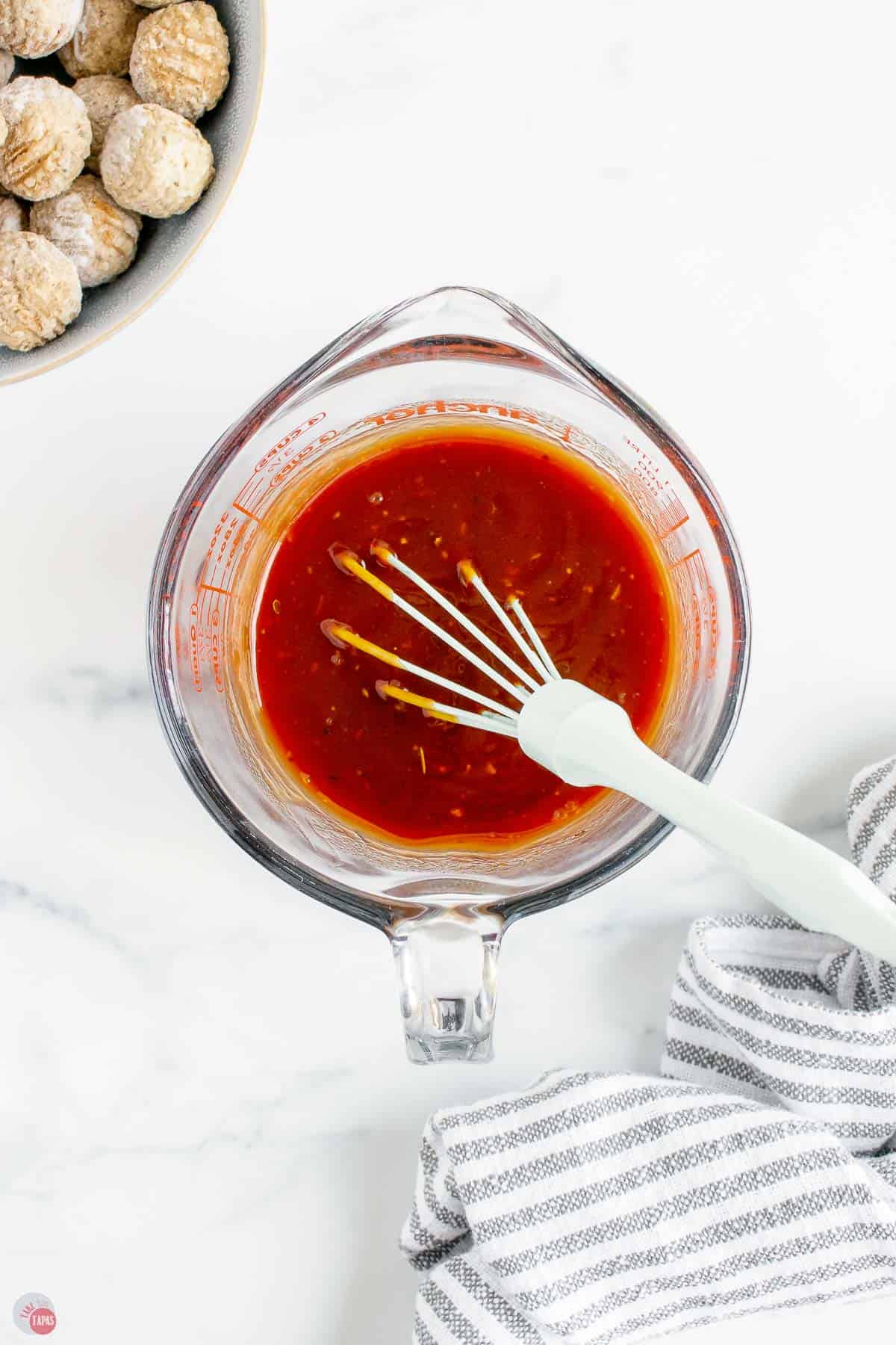 sauce mixing in a clear bowl with whisk