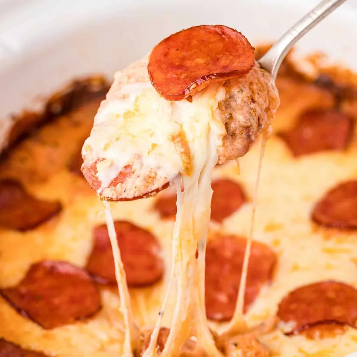 spoon scooping crockpot pizza dip out of slow cooker bowl