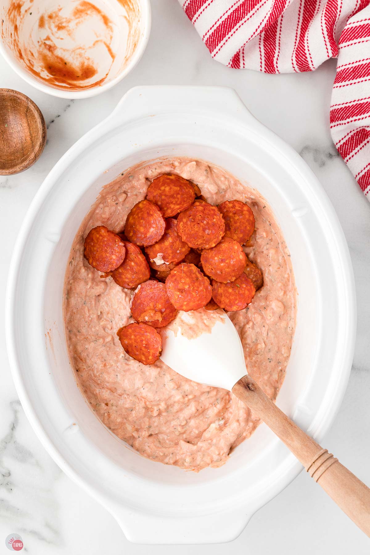 pepperoni on top of pink dip mixture in a white bowl