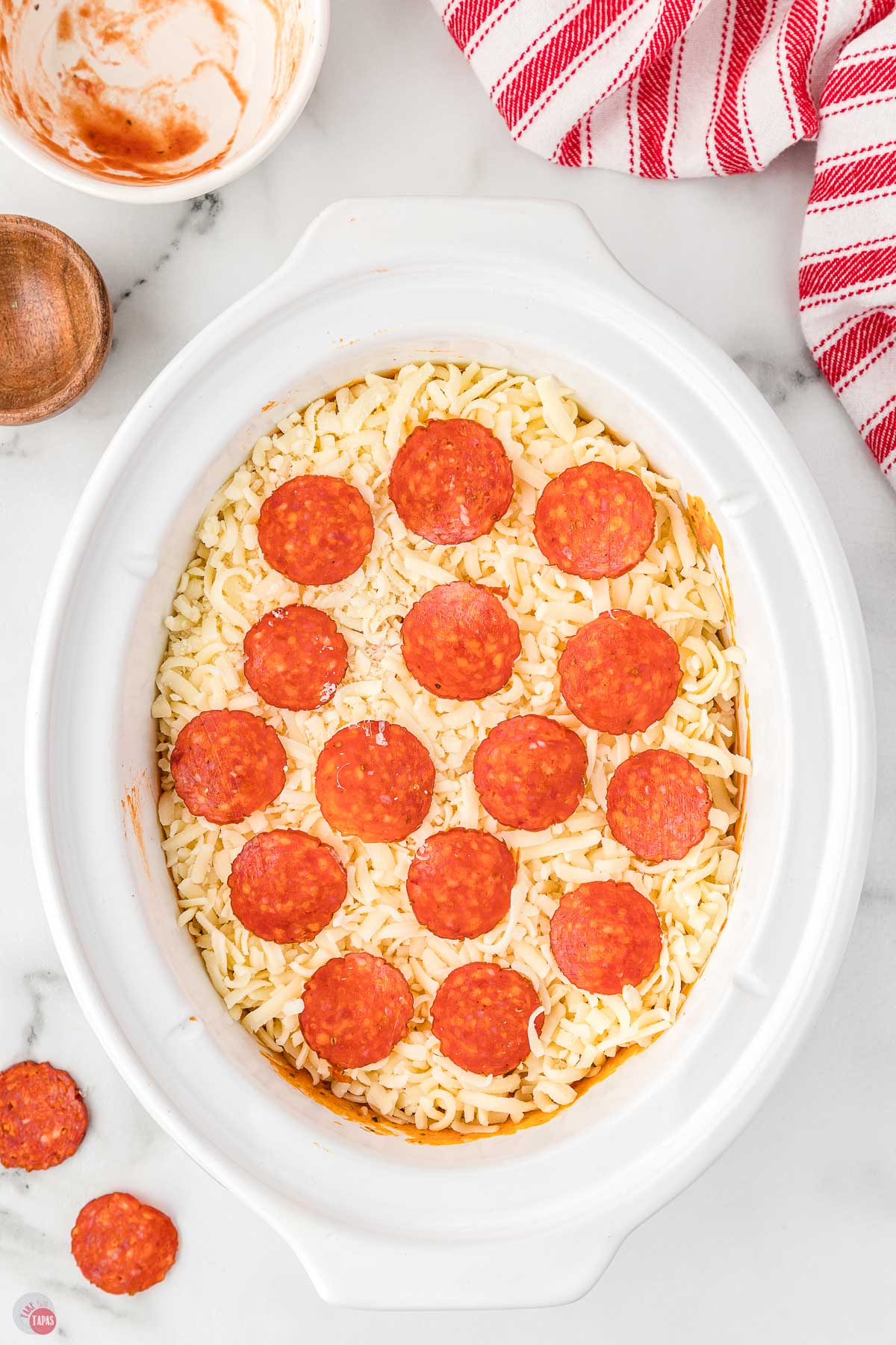 white crock pot filled with shredded cheese and pepperoni slices