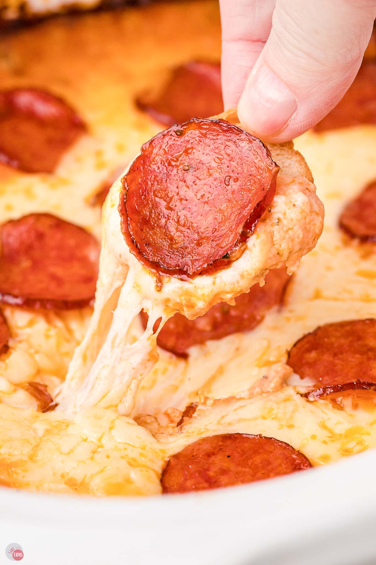 hand pulling pizza dip out of crockpot