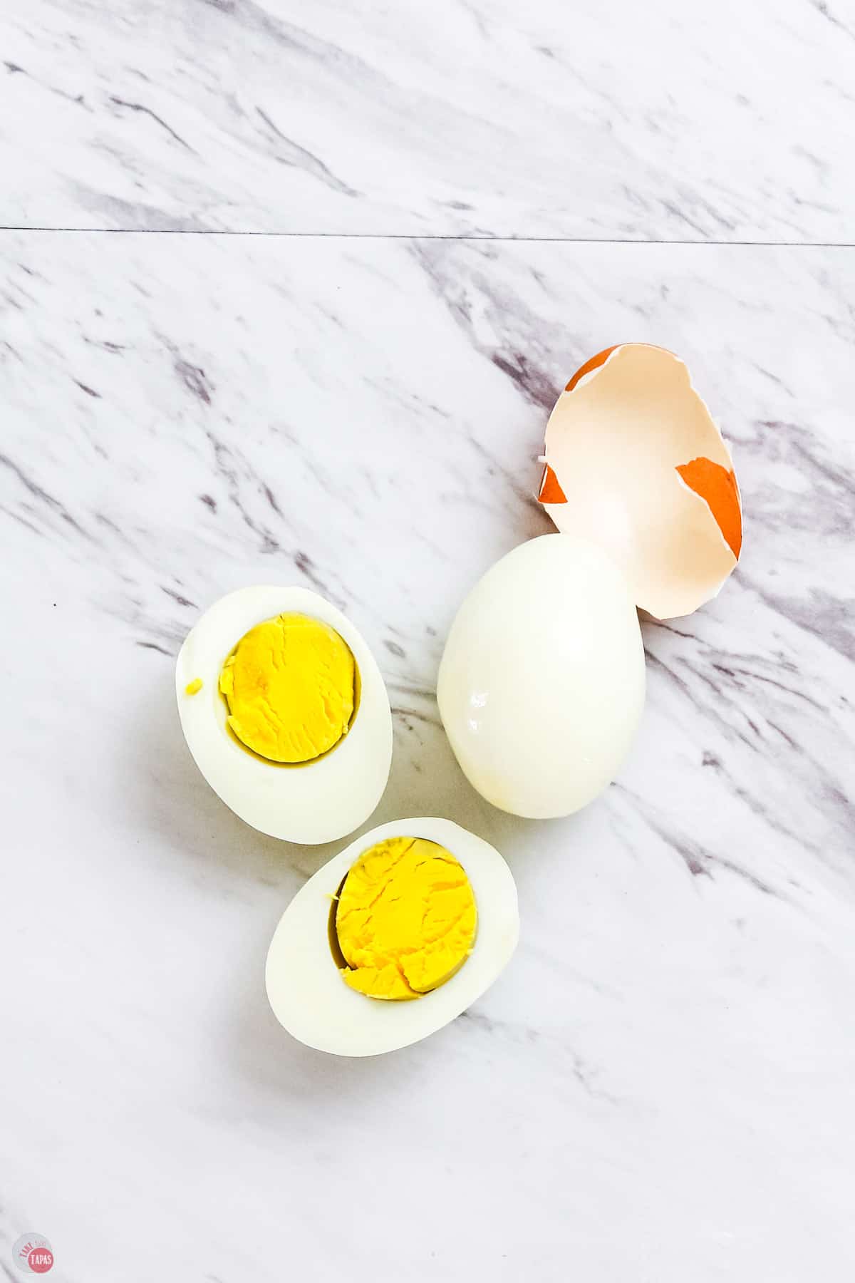 hard boiled eggs on a marble backdrop with an egg shell