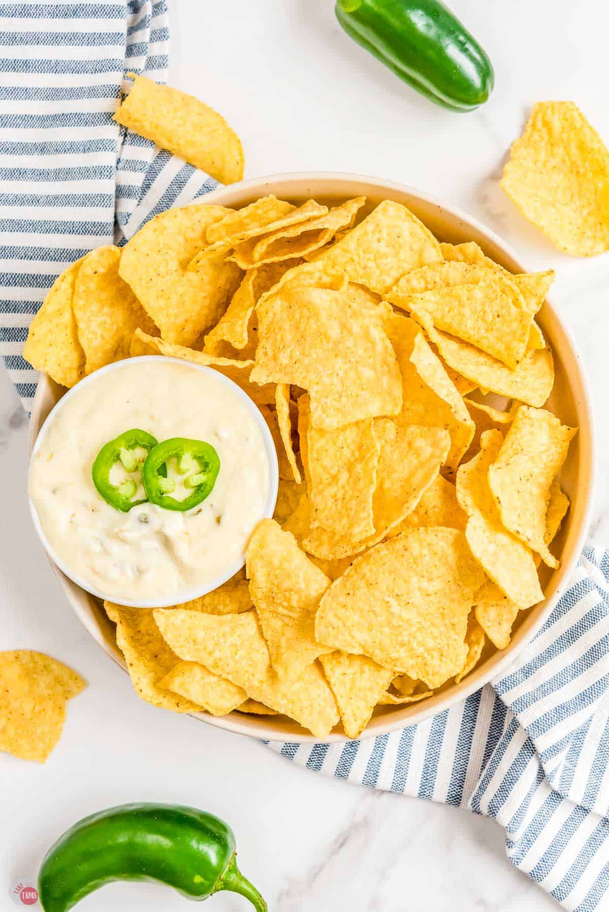 overhead picture of bowl of chips and a smaller bowl of dip with blue and white striped napkin