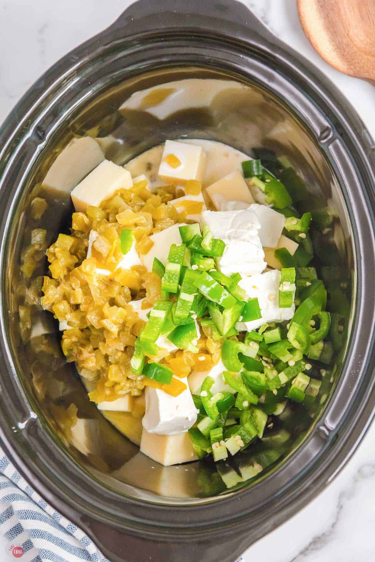 slow cooker with cubes of cheese and green chilies