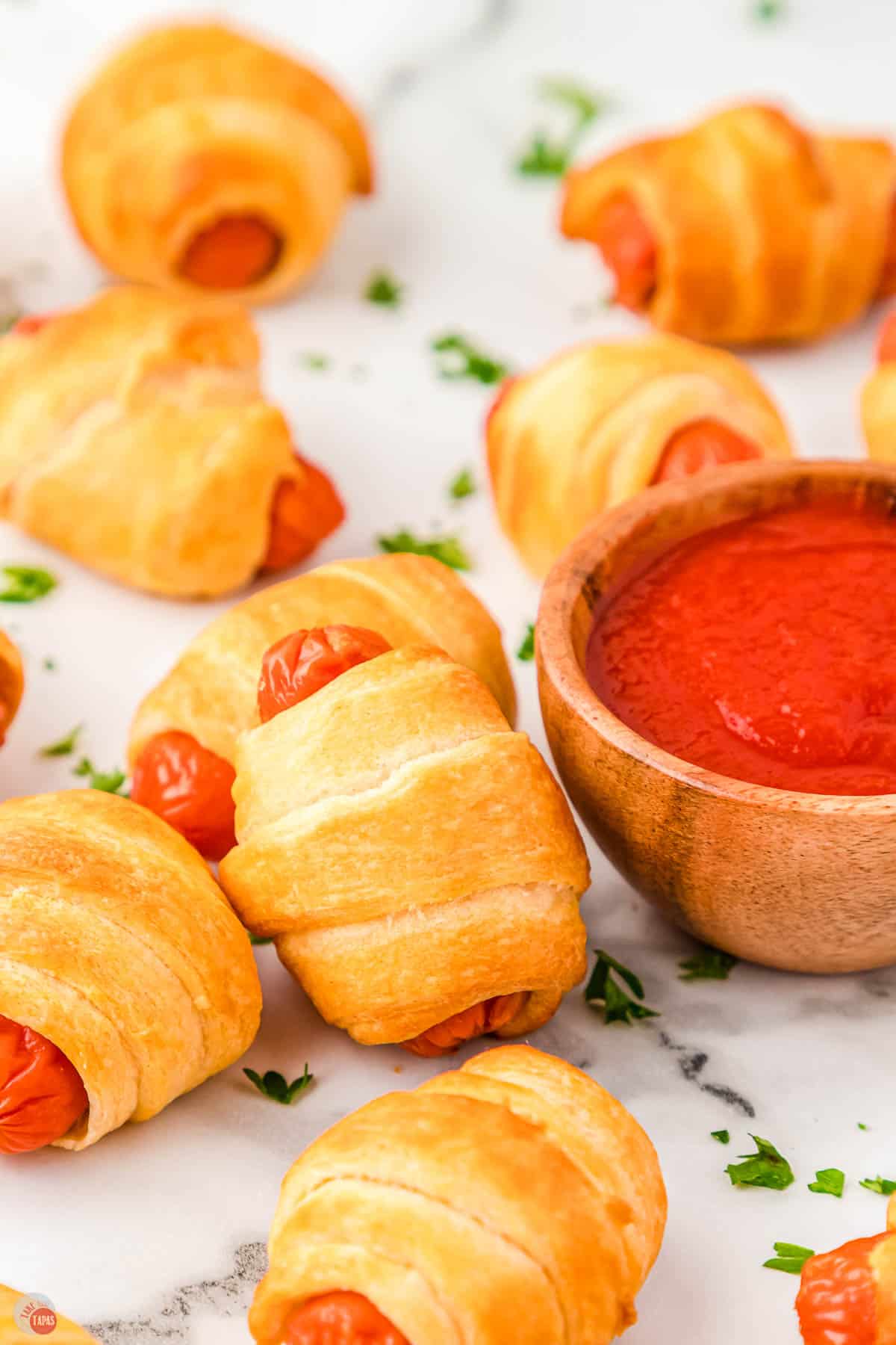 wrapped sausages next to a bowl of ketchup