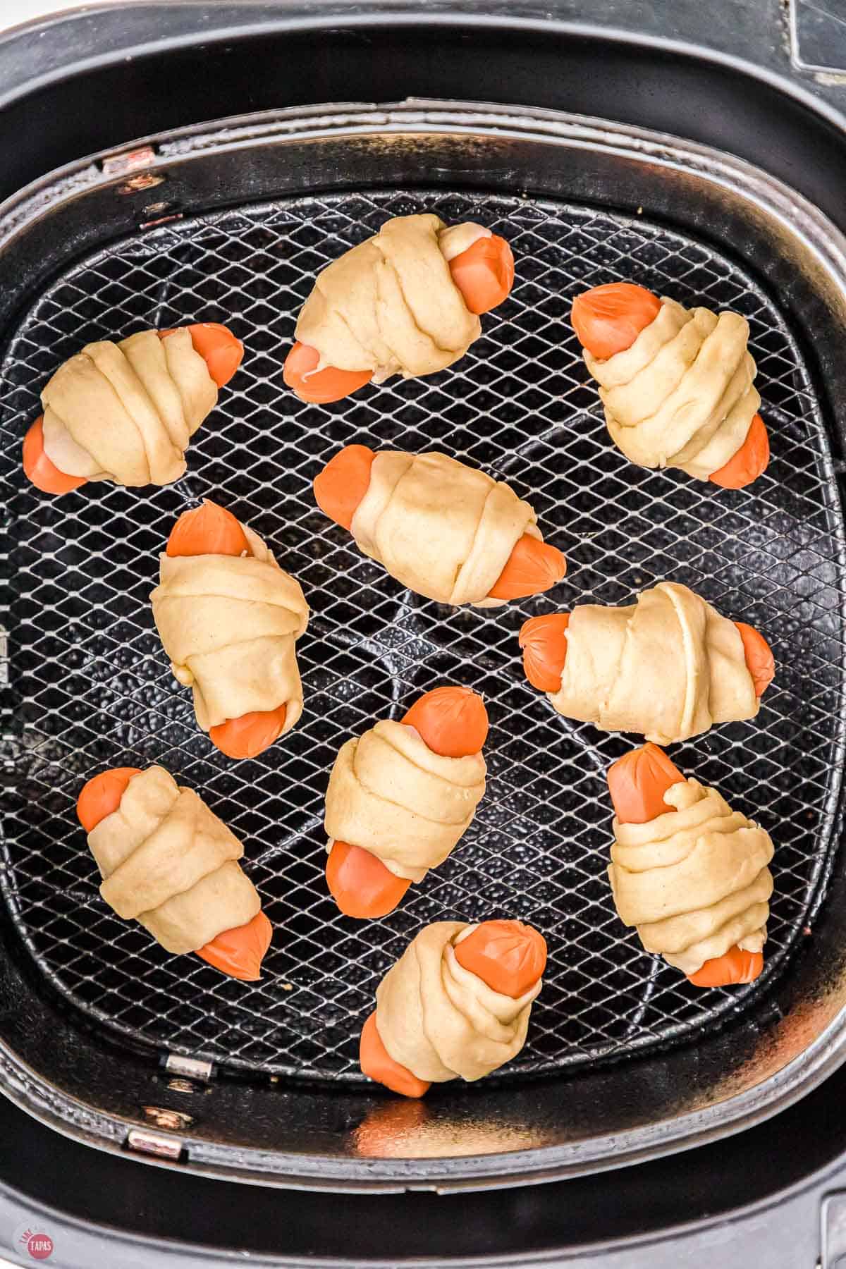 uncooked pigs in a blanket in an air fryer basket