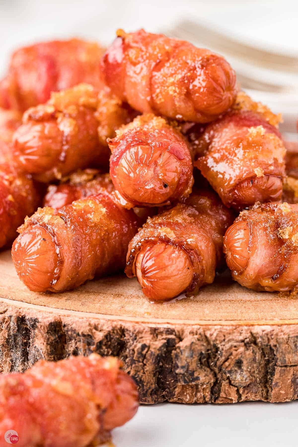 pile of bacon wrapped lil smokies on a wood platter