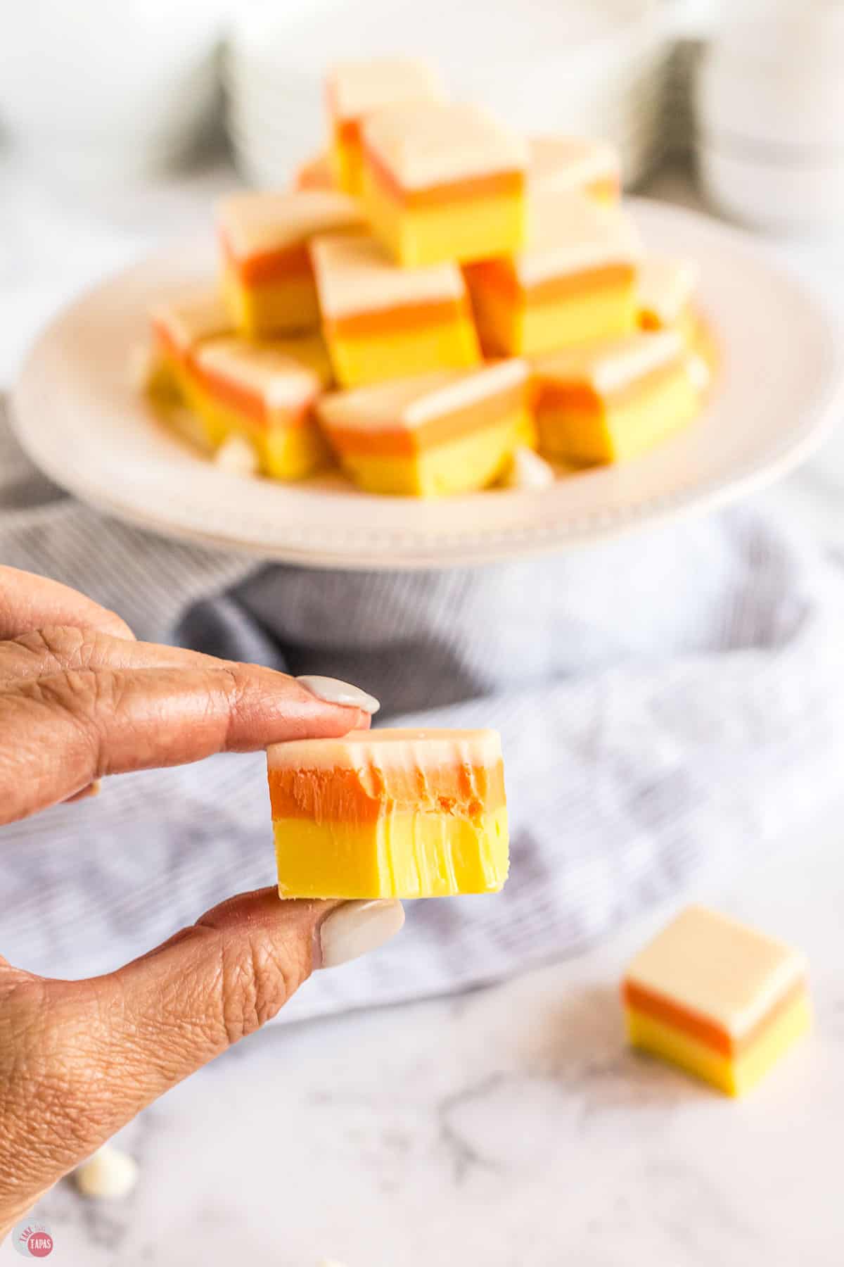 hand holding candy corn fudge with a bite in it