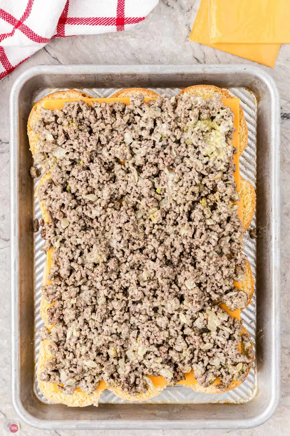 ground beef on top of buns on a baking dish