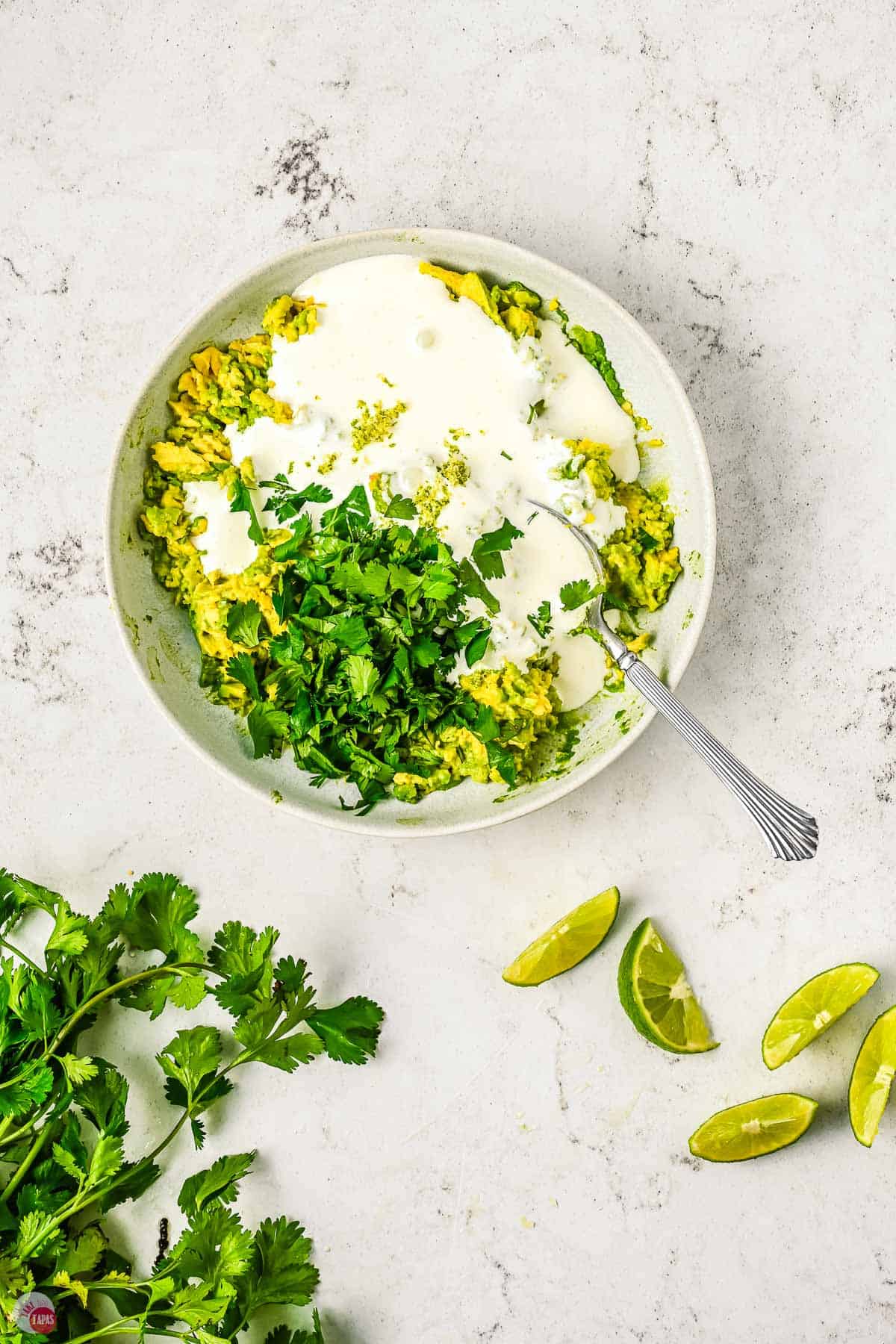 unmixed avocado dipping sauce in a bowl with a spoon