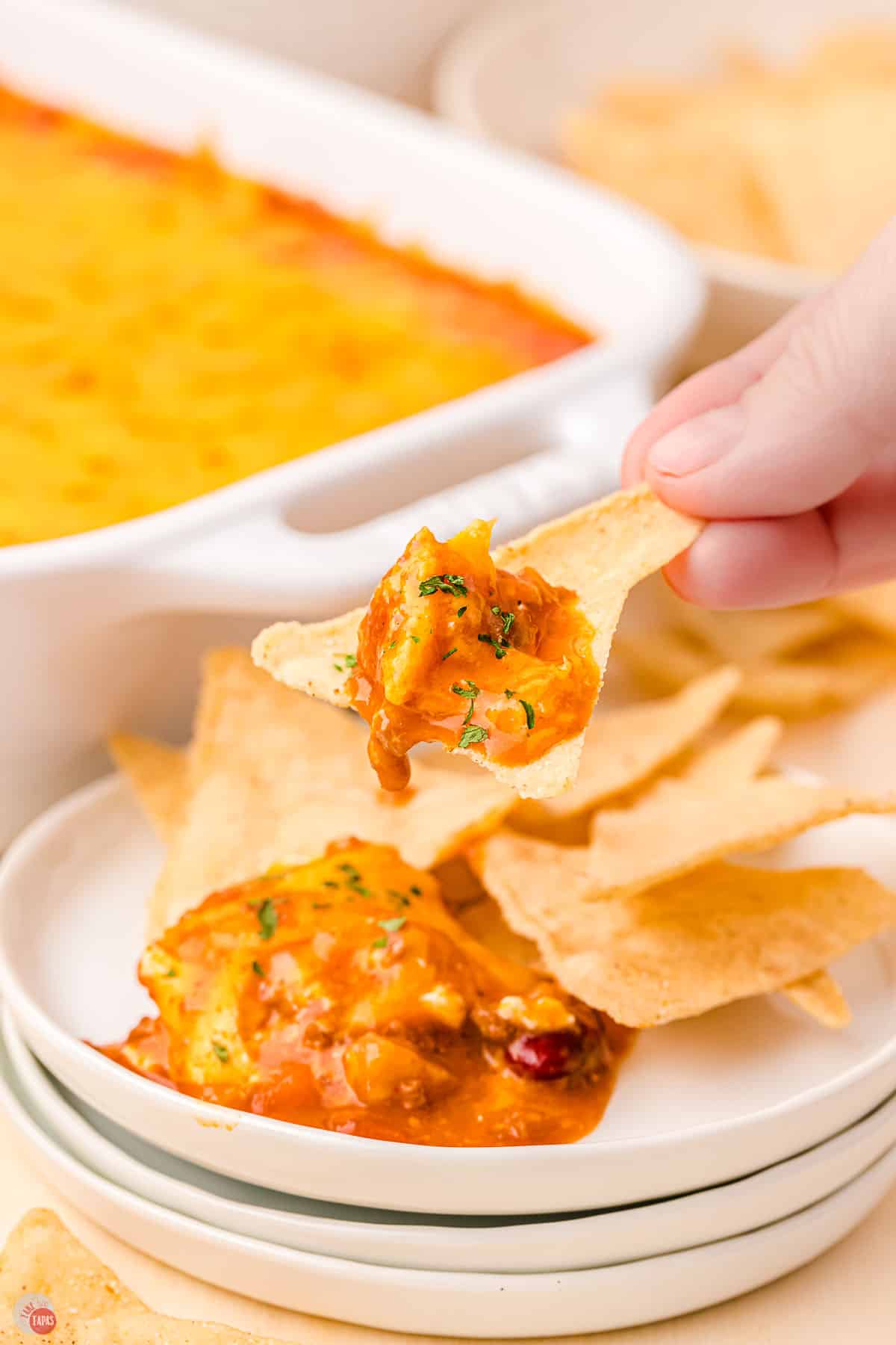 hand holding chip over a plate of chips and dip