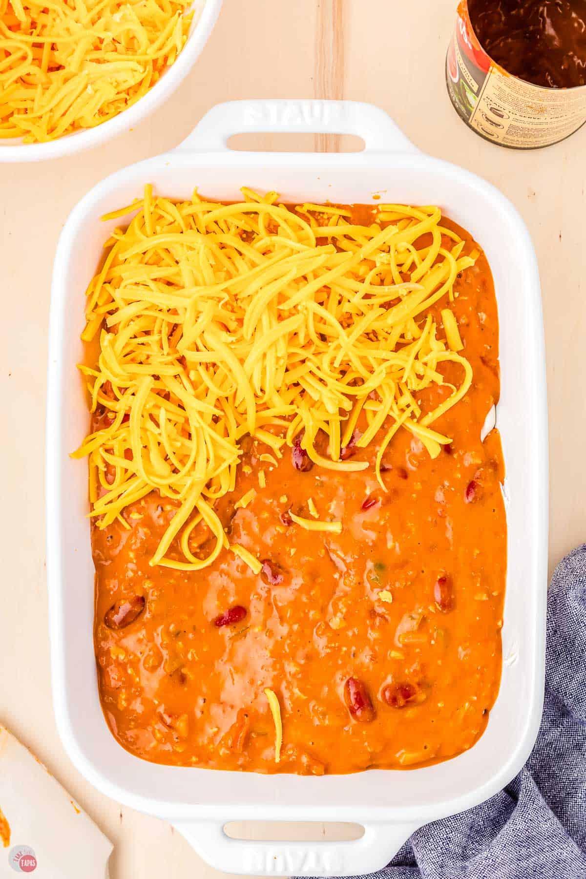 chili half topped with shredded cheese in a white rectangle dish