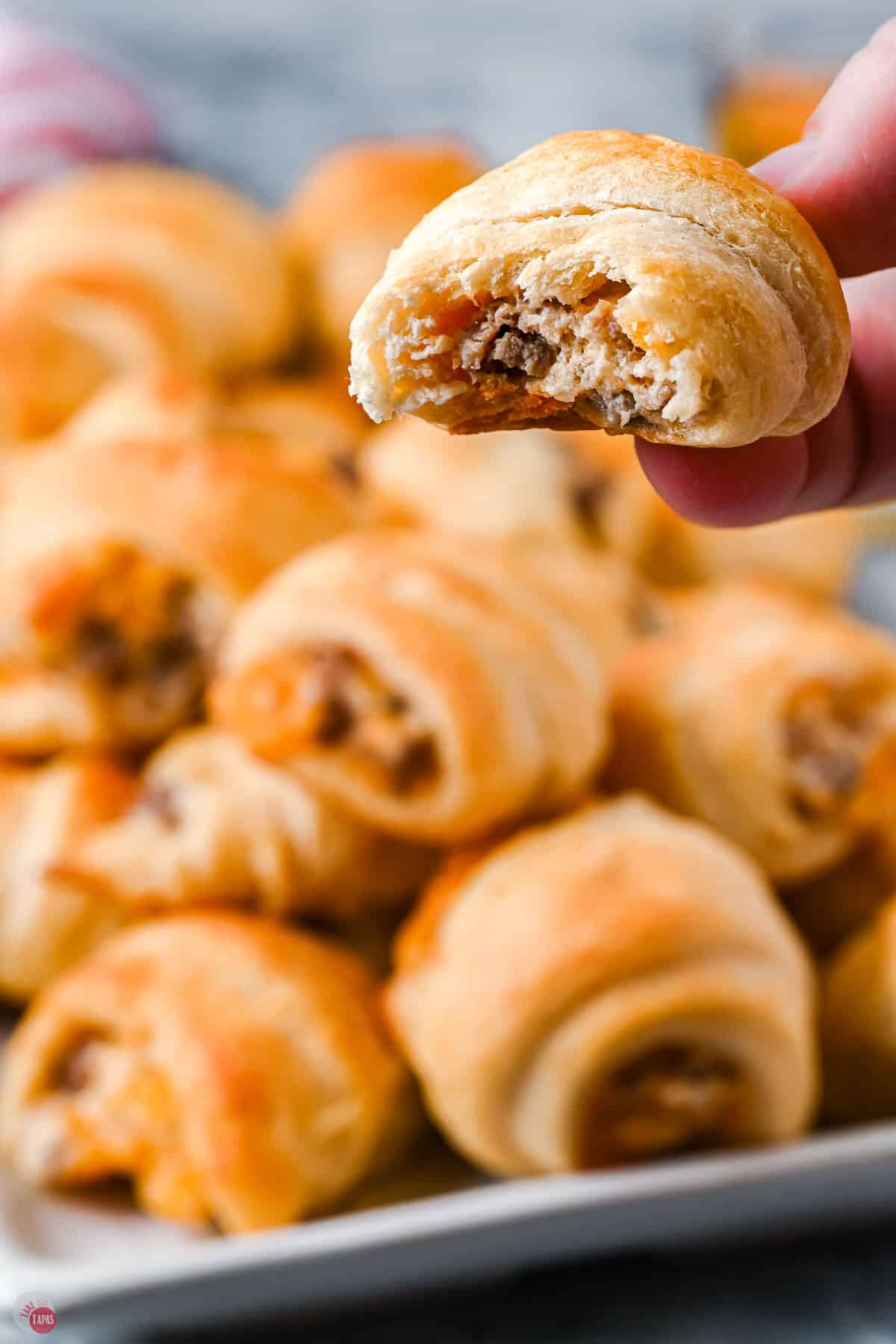 crescent rolls with a hand holding one with a bite missing