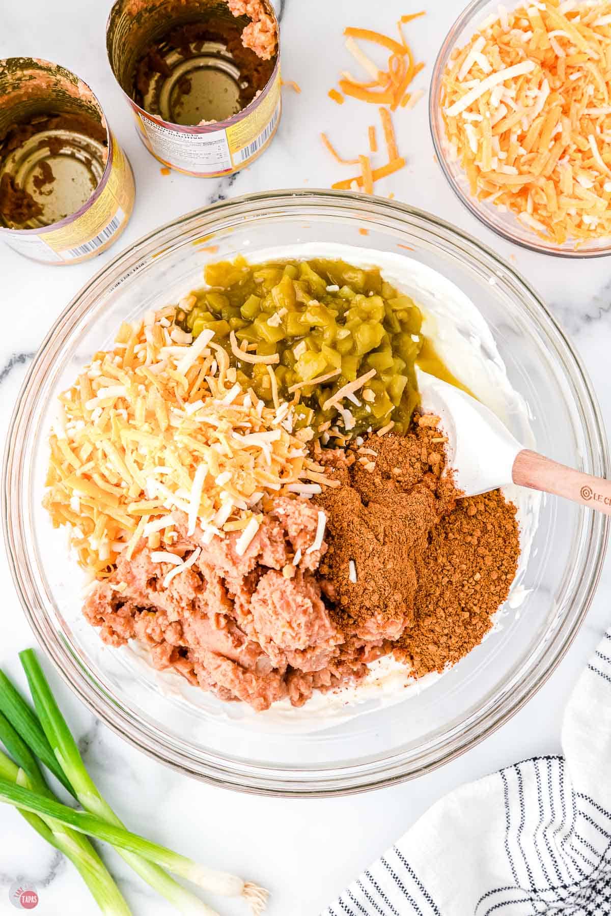 bowl of cheese, seasoning, and refried beans with white spatula