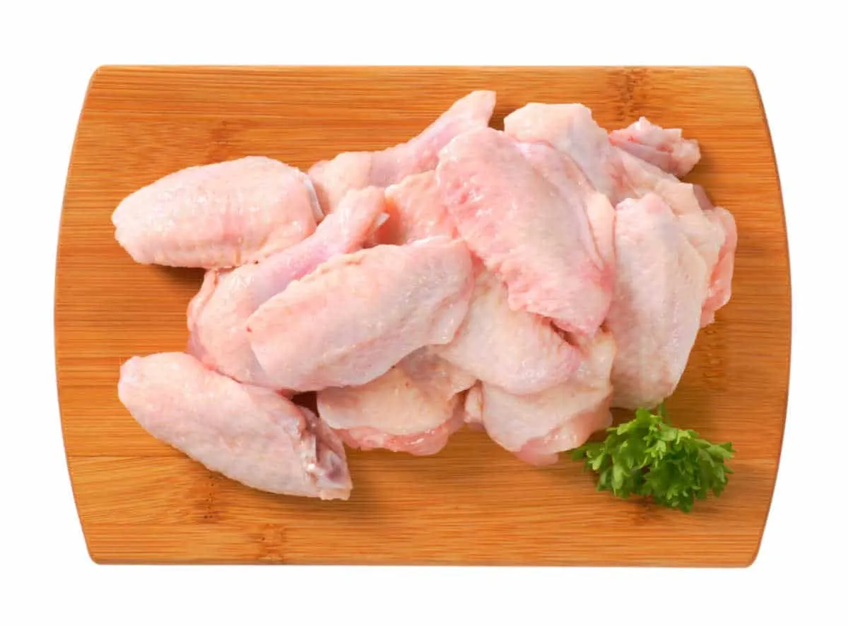 raw chicken wings on a wood board
