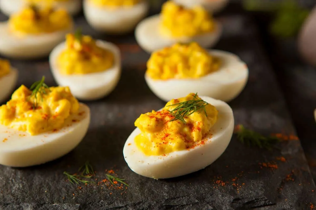 mustard deviled eggs on a dark board
