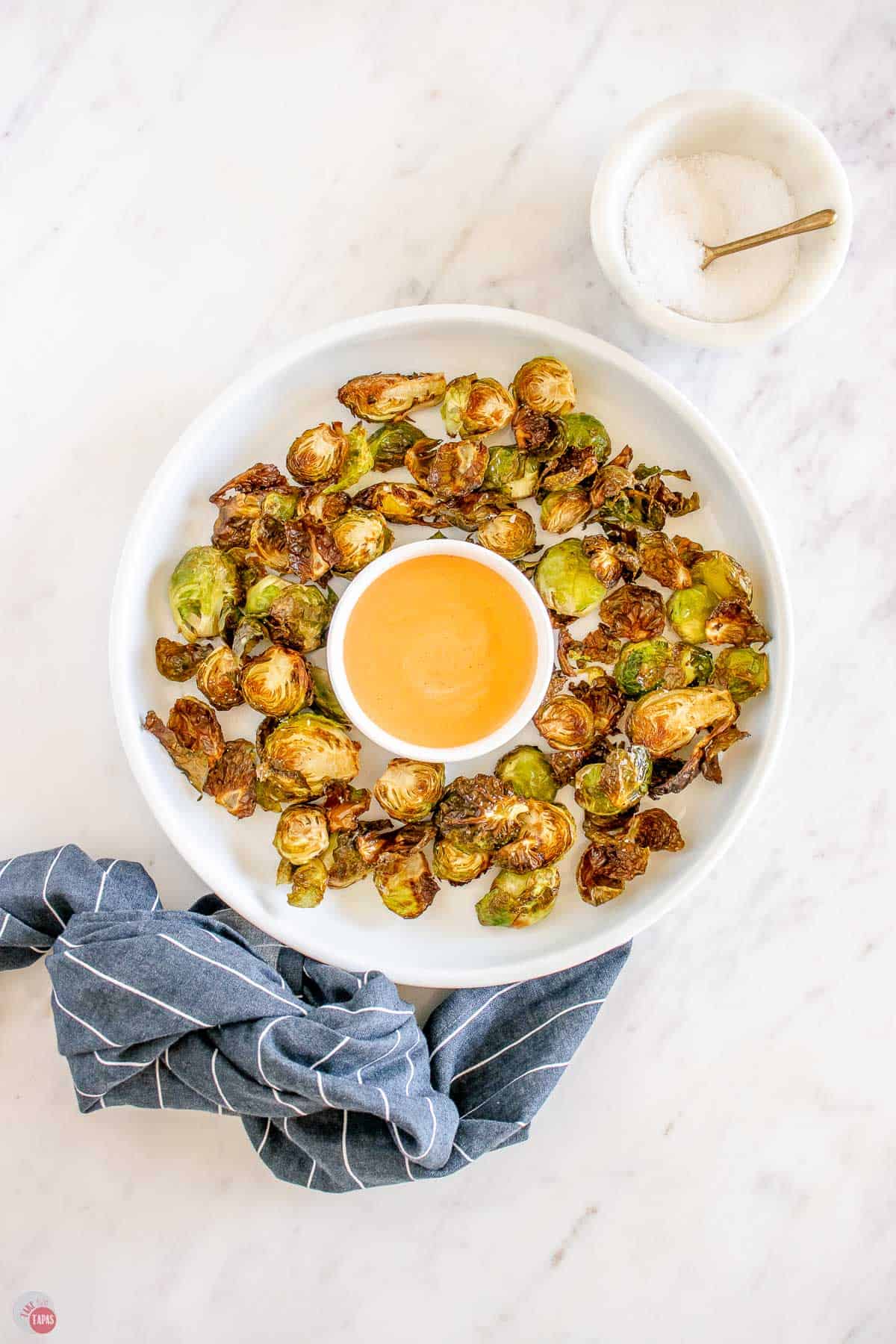 overhead picture of bowl of sprouts with dipping sauce and a blue napkin