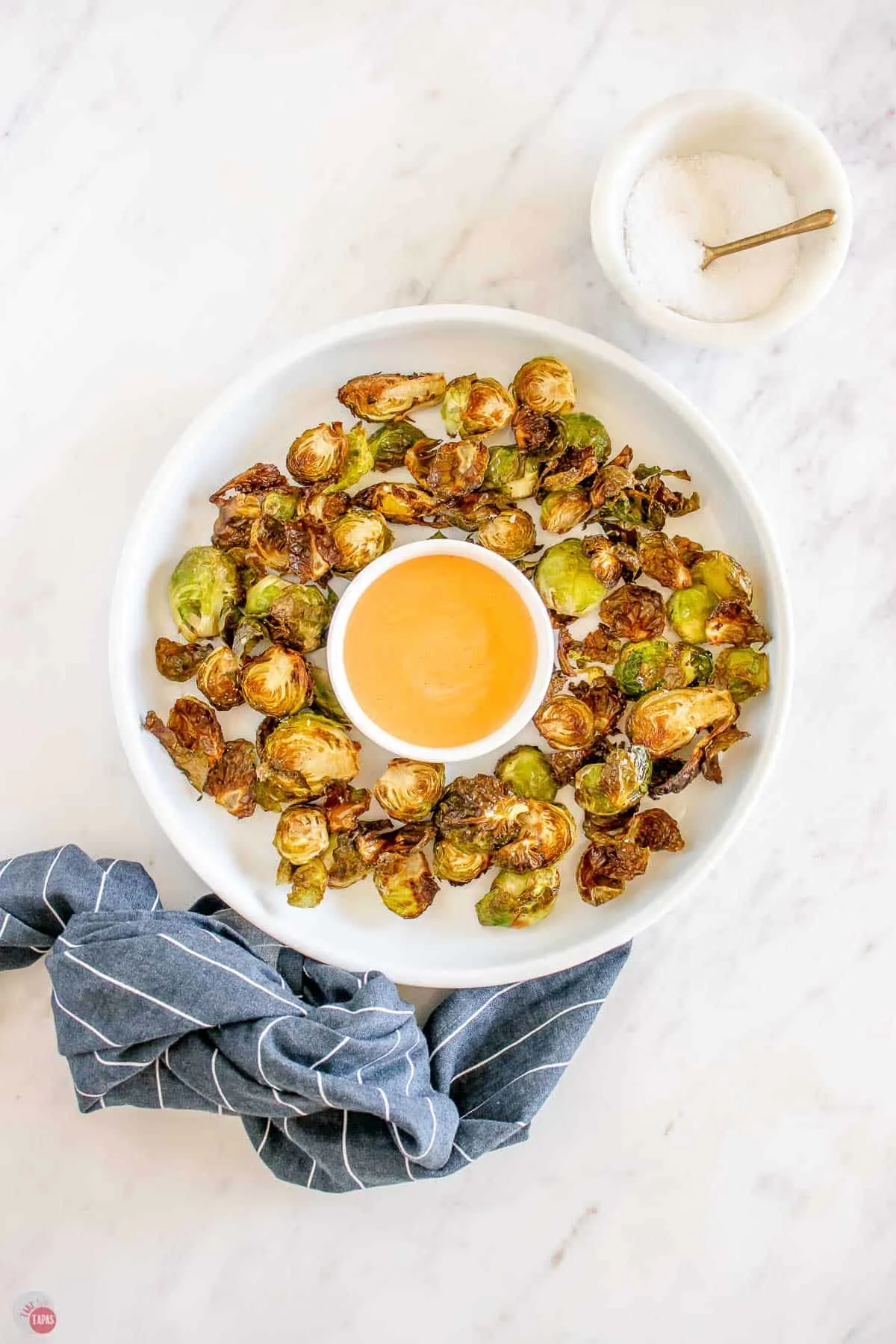 overhead picture of bowl of sprouts with dipping sauce and a blue napkin