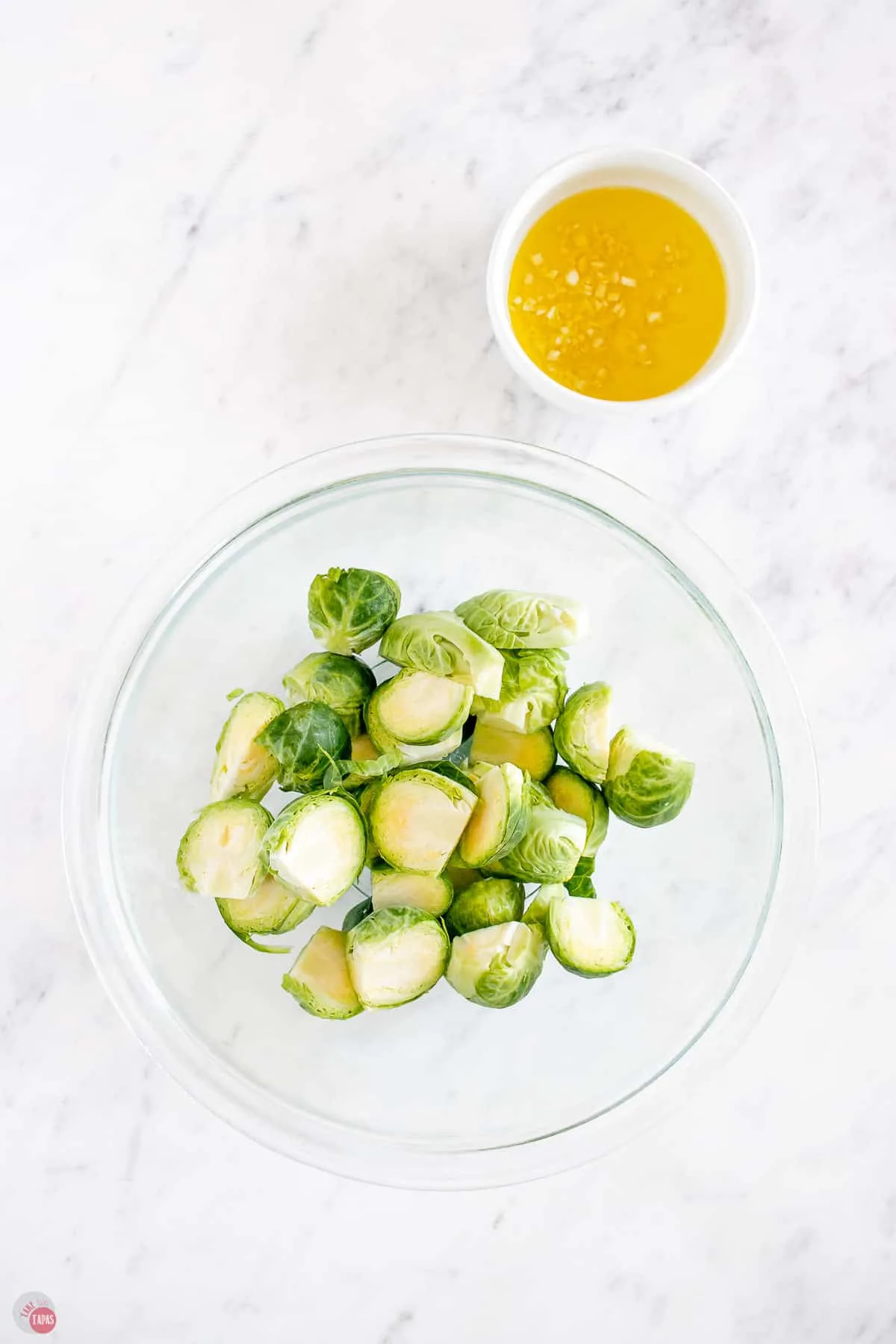 sprouts in a bowl with garlic and olive oil next to it