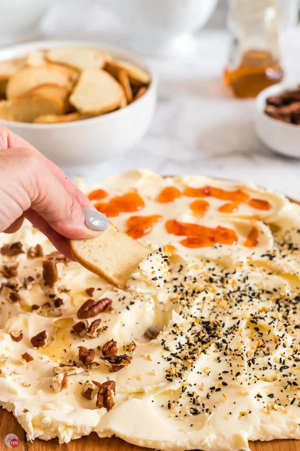 bagel chip being dipped into butter and seasoning