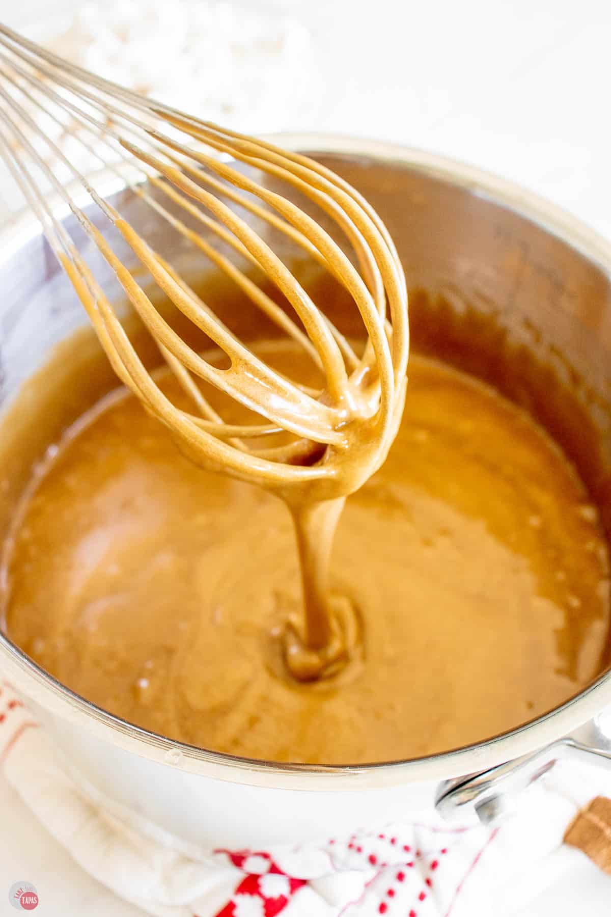 whisk with caramel sauce over a pot