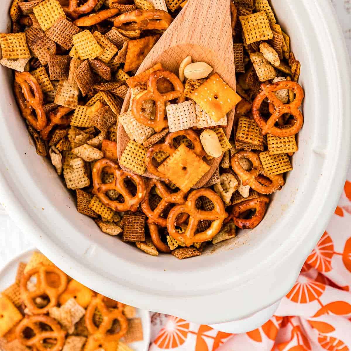 slow cooker with chex mix and a wood spoon