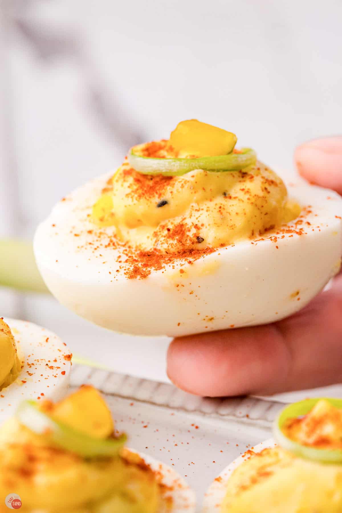 hand holding a deviled egg topped with paprika