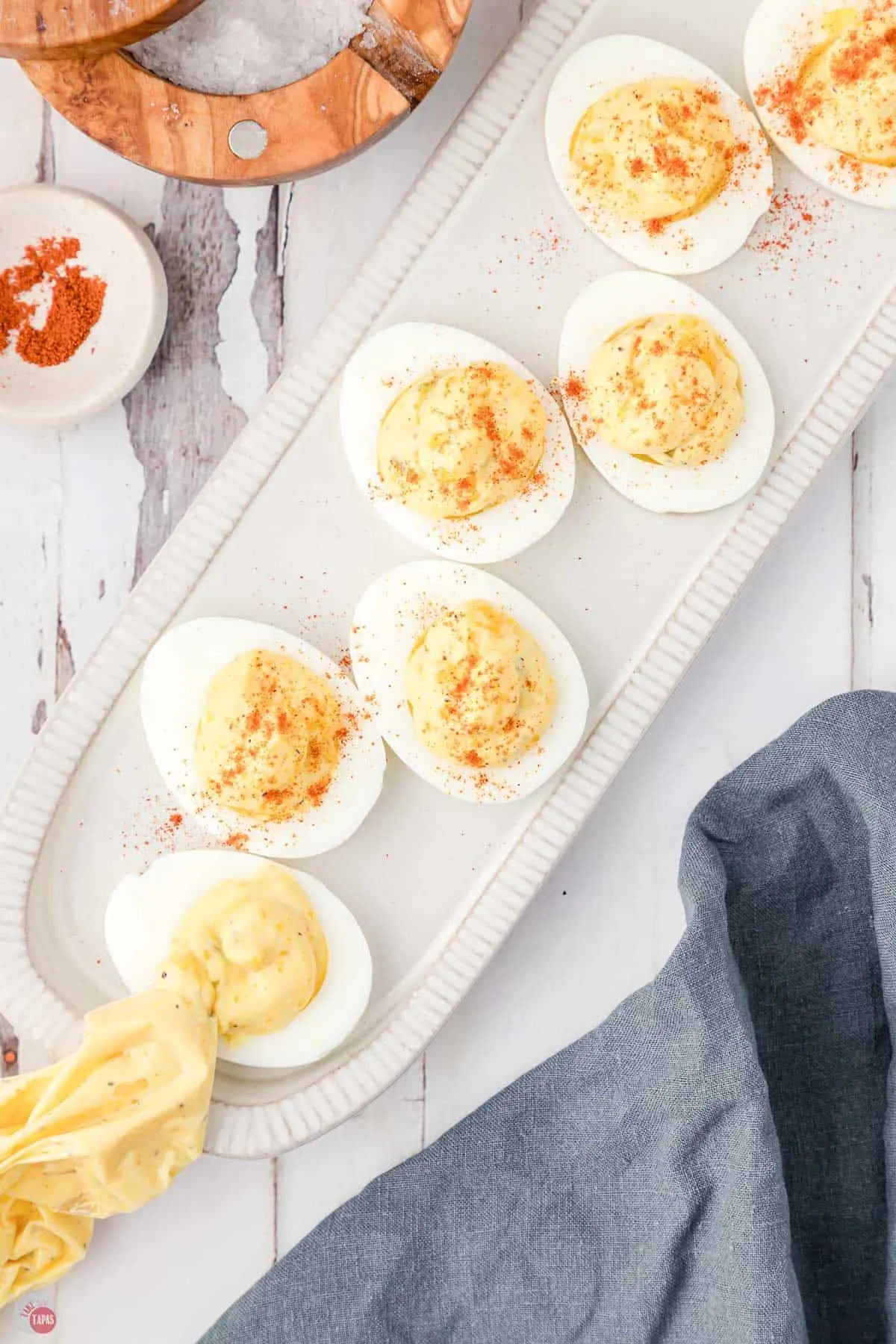 piping bag with yolk mixture next to a pan of egg halves