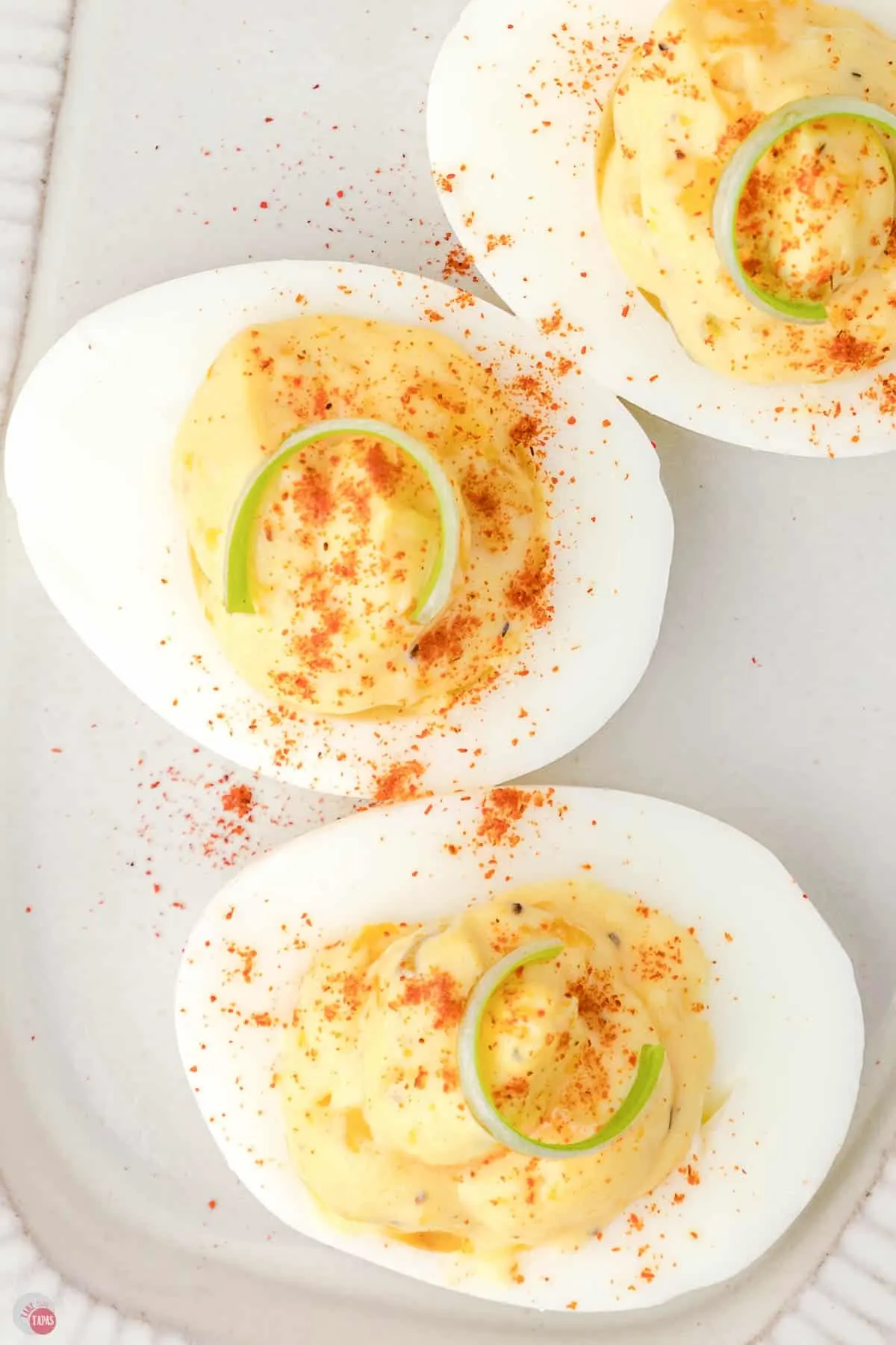 row of deviled eggs on a ceramic plate
