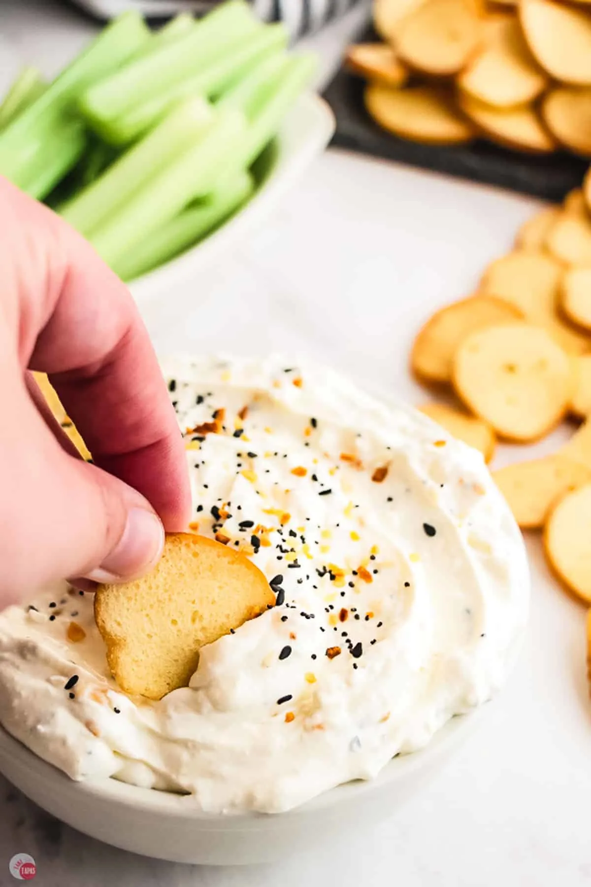 bowl of dip with a bagel chip and a stalk of celery