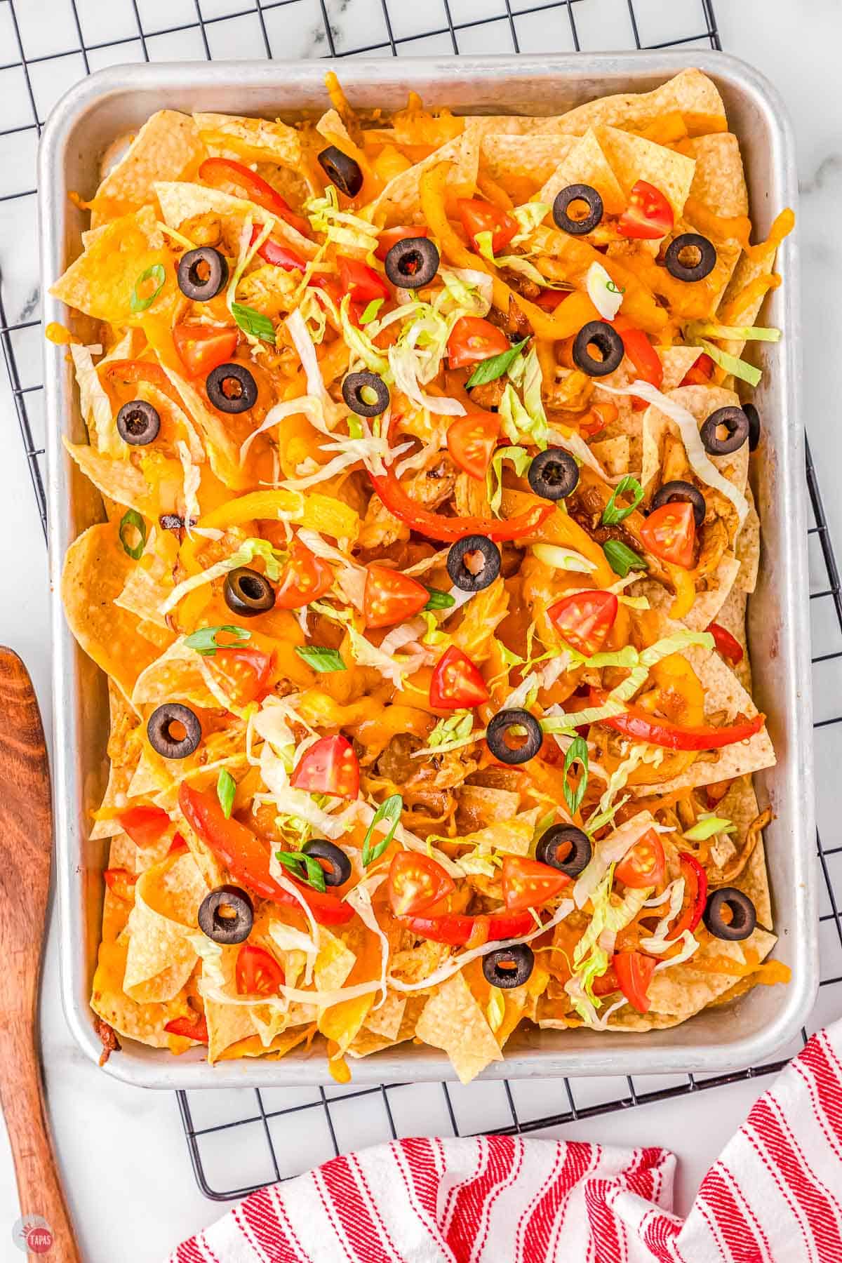 sheet pan of chicken fajita nachos topped with olives and lettuce