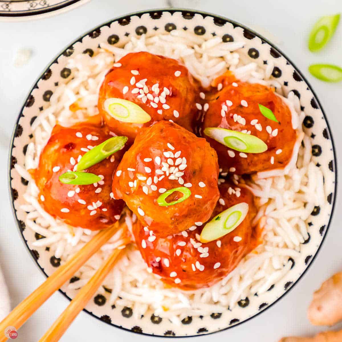 chopstick with meatball over a bowl of rice