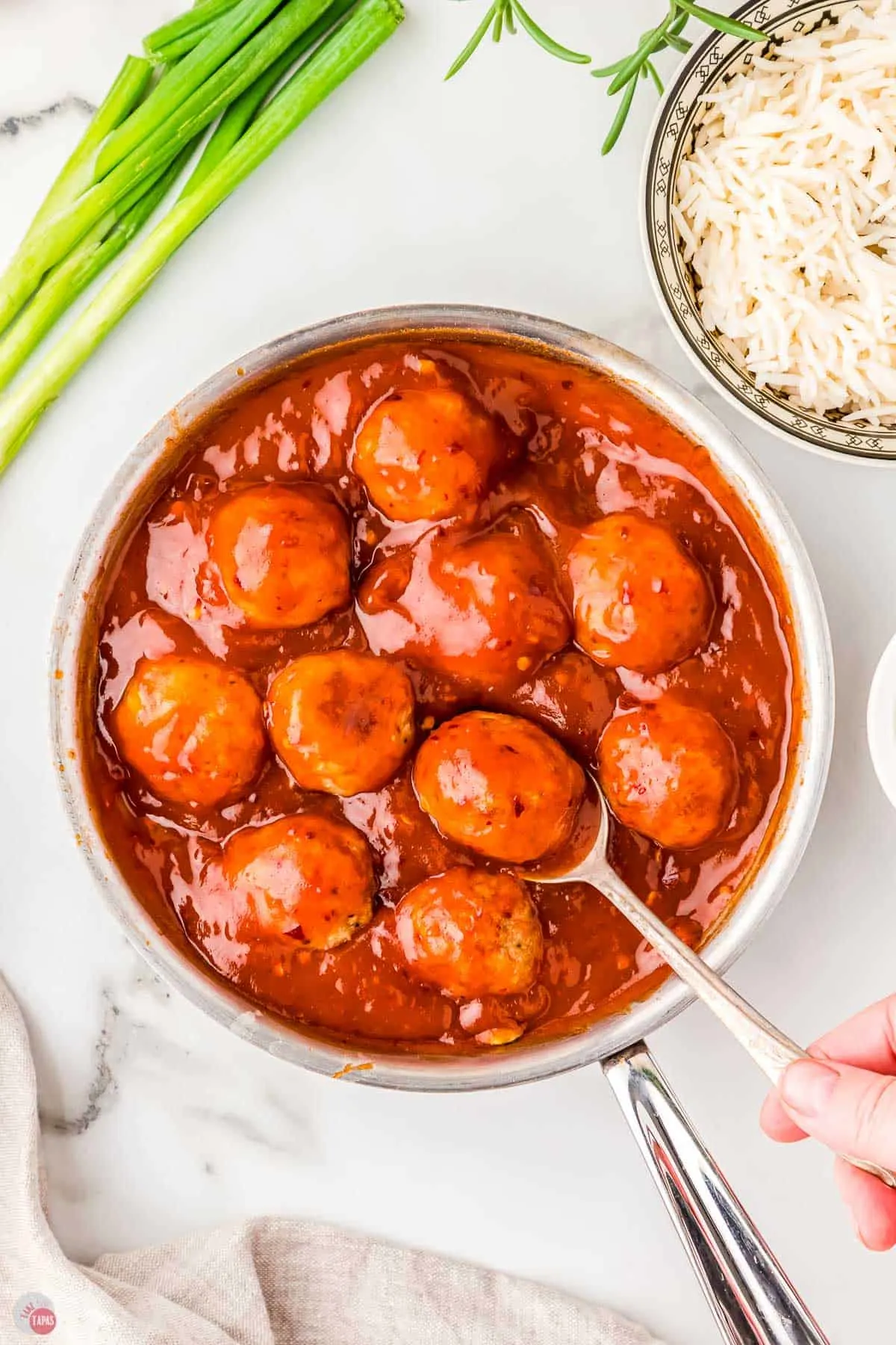 saucepan with meatballs and sauce with a spoon