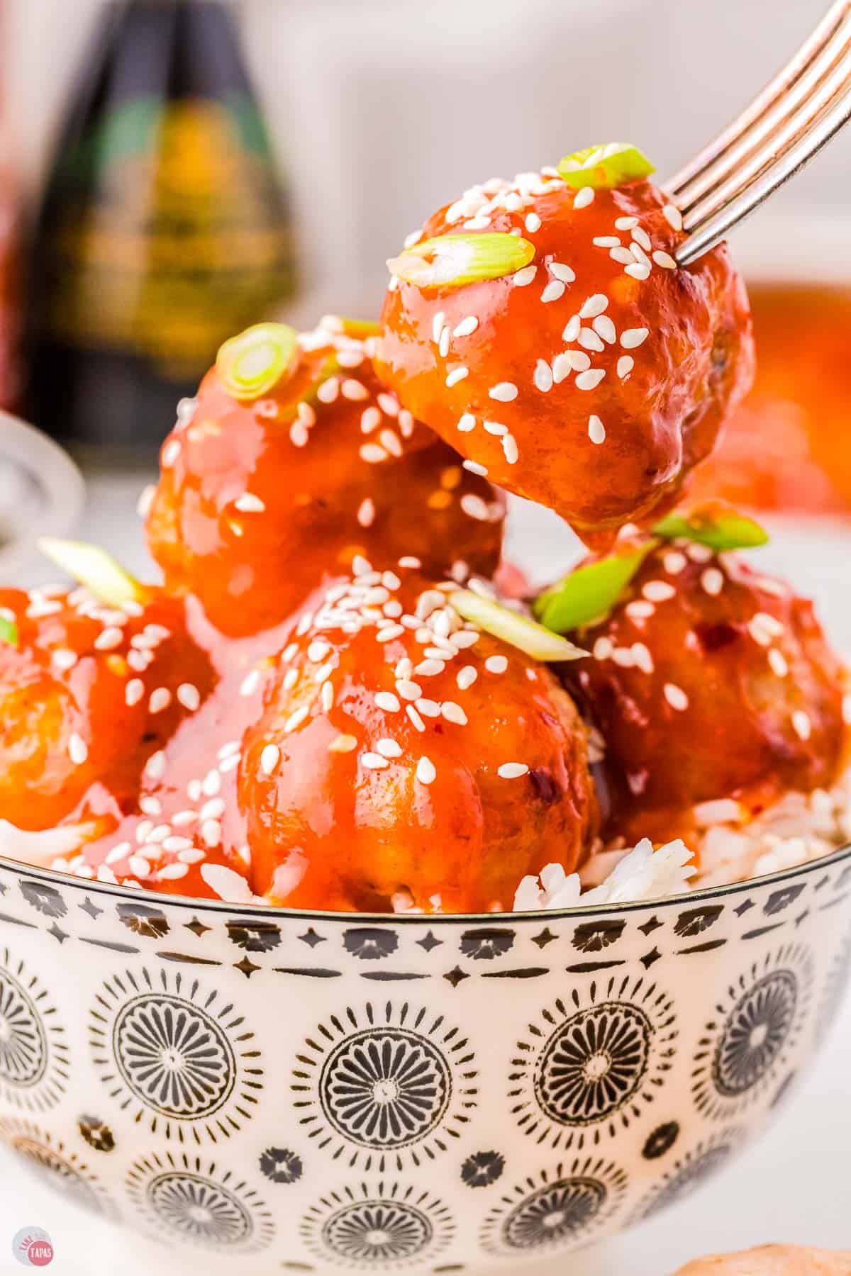 fork with meatball over a bowl of rice