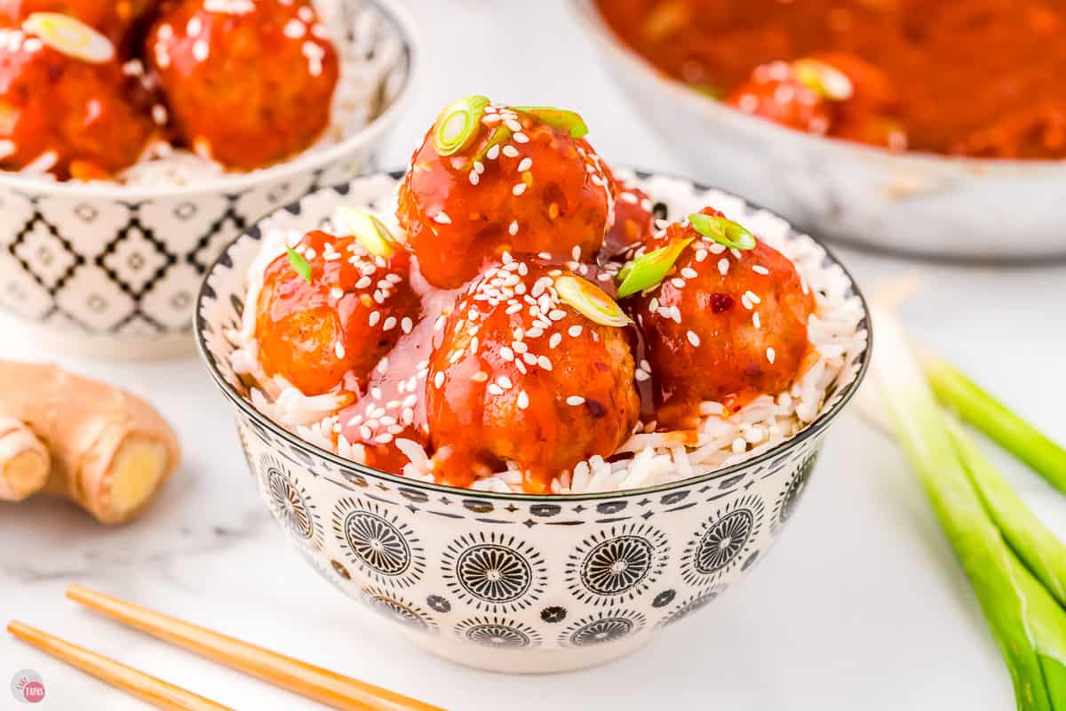 bowl of firecracker meatballs recipe over white rice next to chopsticks