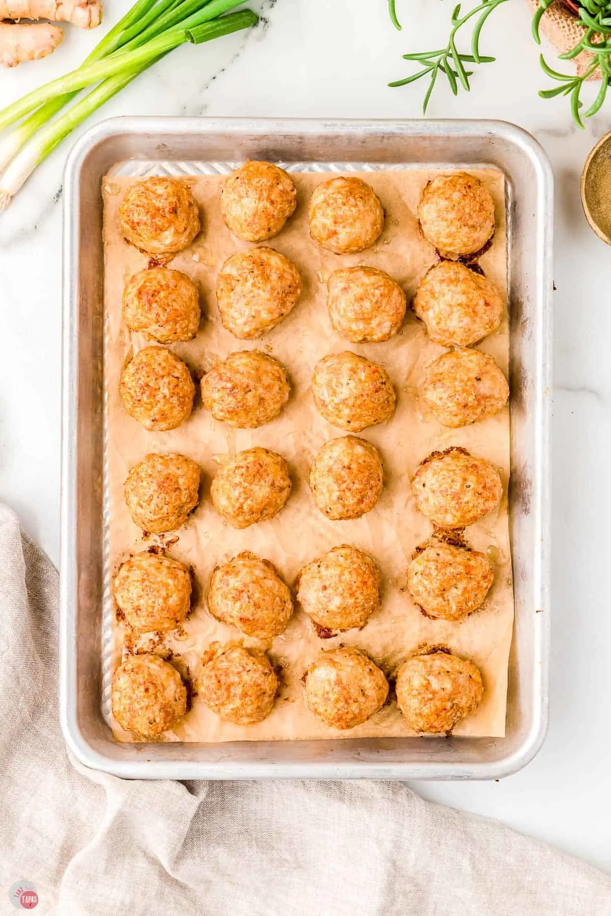 baked meatballs on a cookie sheet with parchment paper