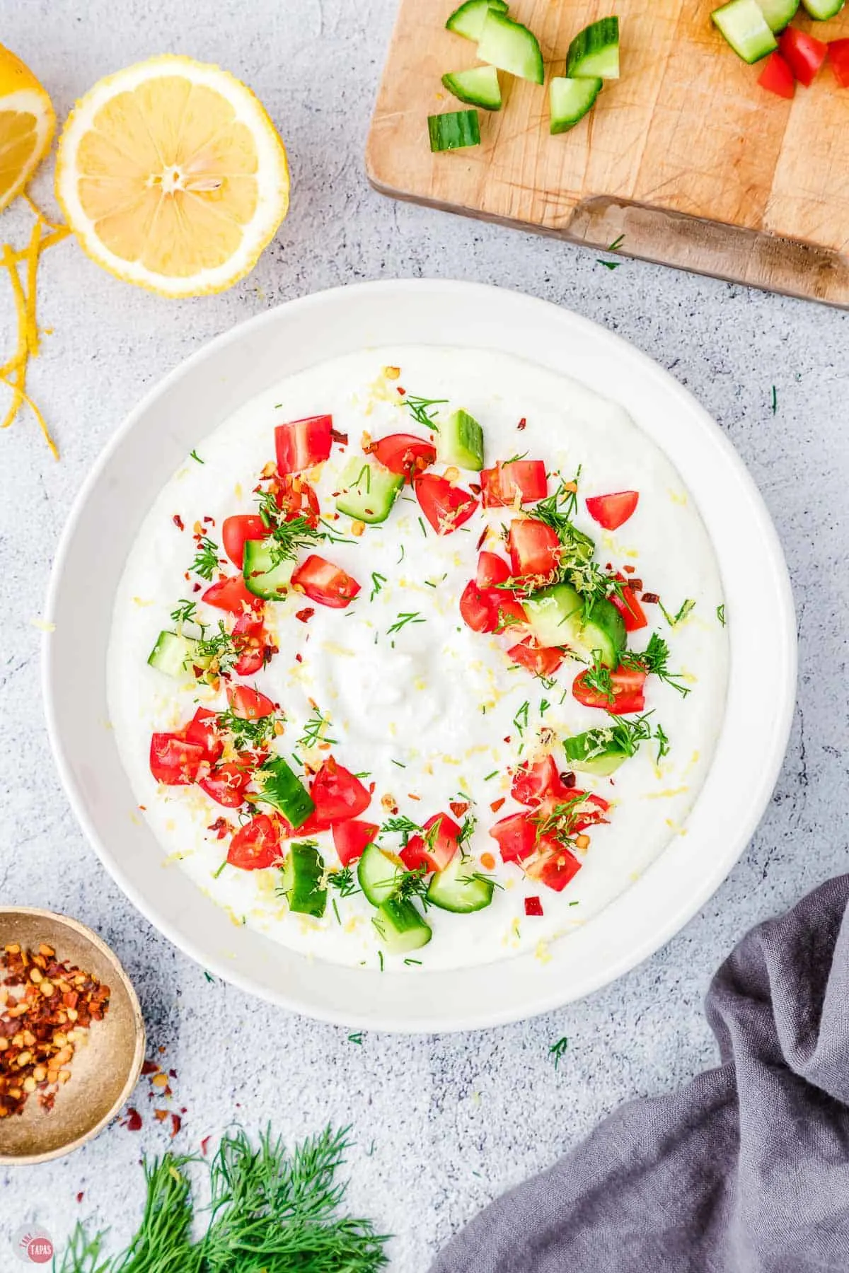 feta dip in a bowl topped with diced tomatoes and diced cucumbers