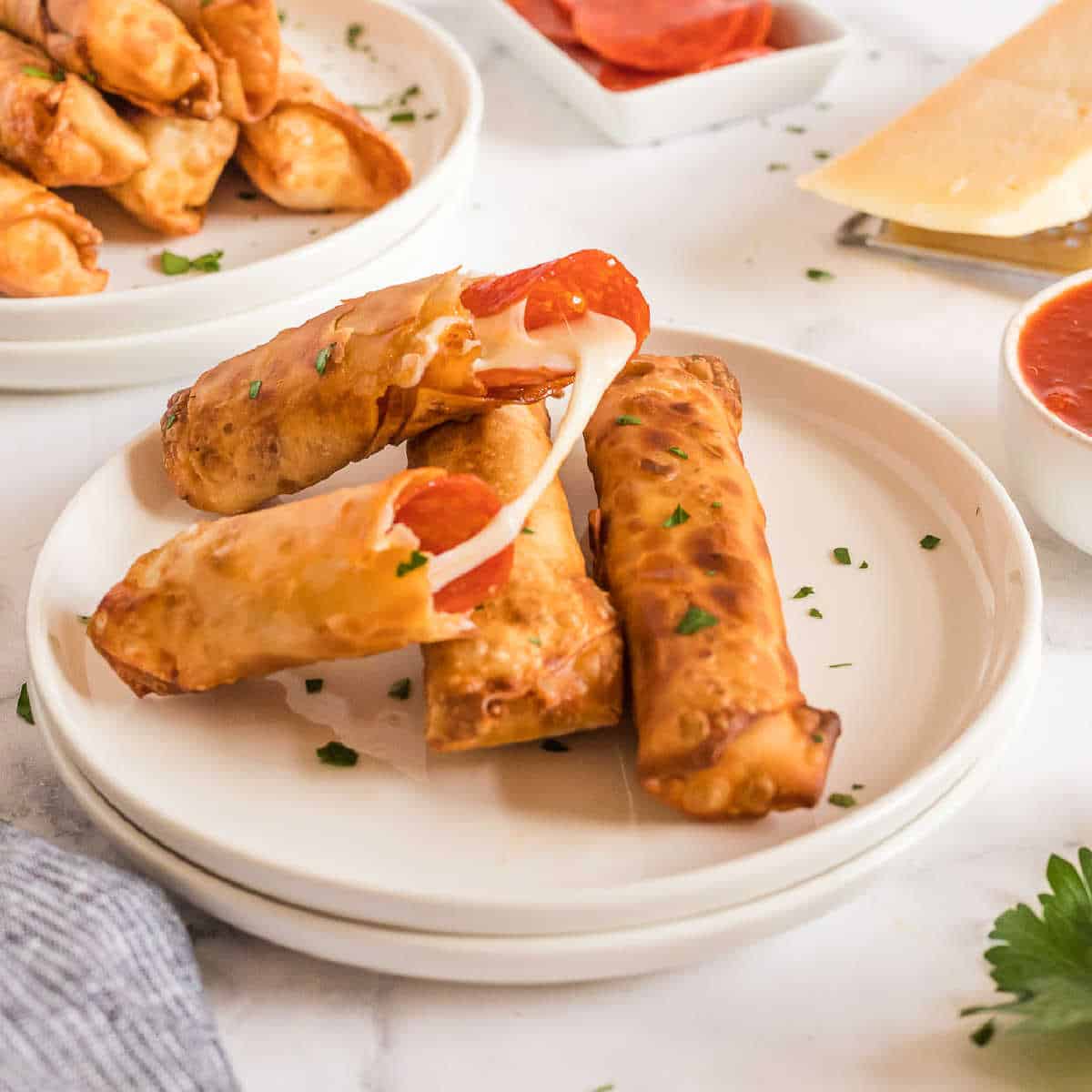 plate of three egg rolls with one torn open and cheese melting out