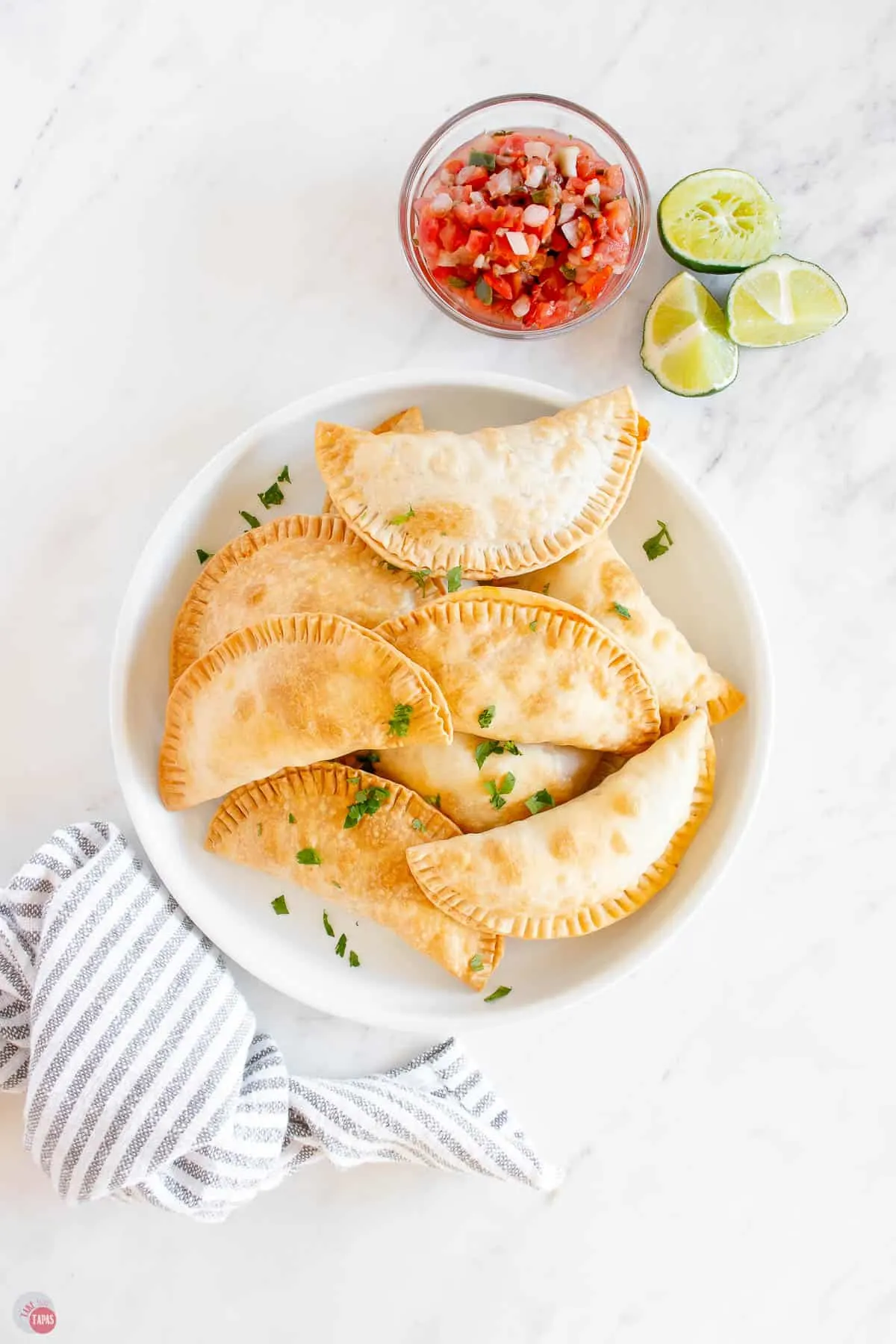 stack of corn empanadas next to bowl of pico