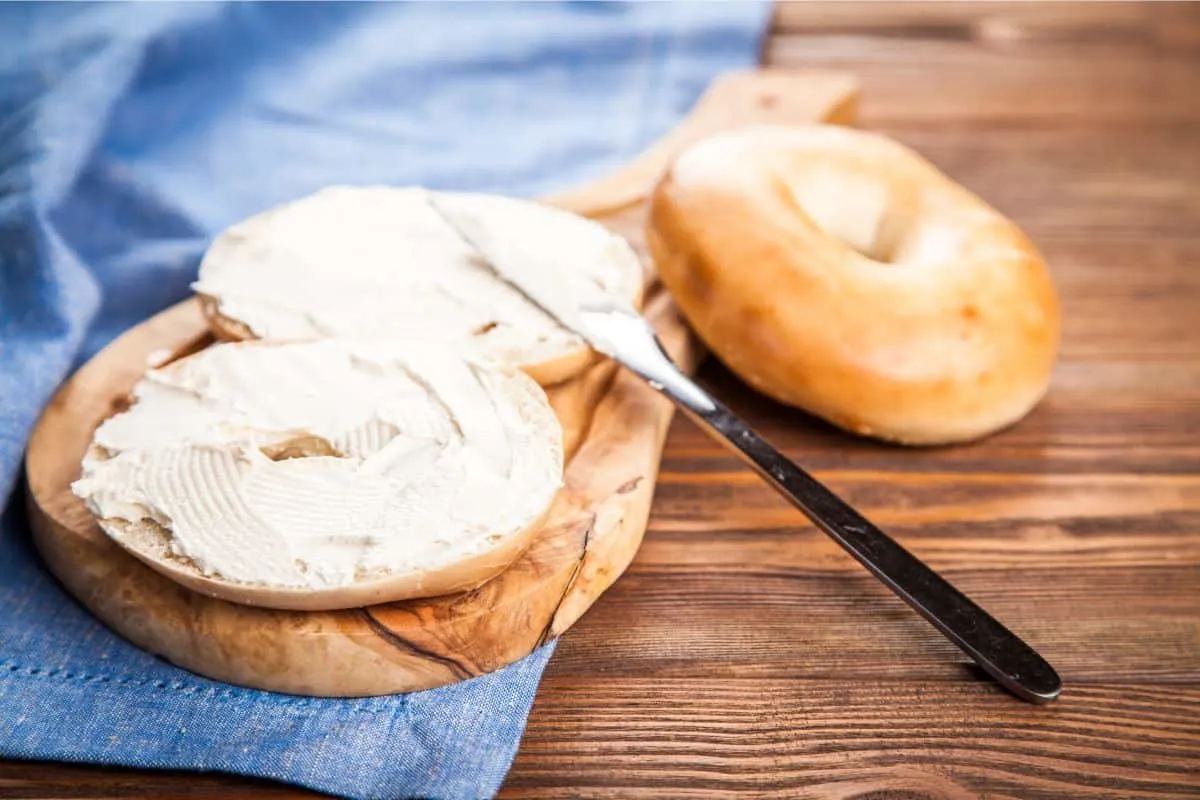 bagel with cream cheese smeared on it with a butter knife