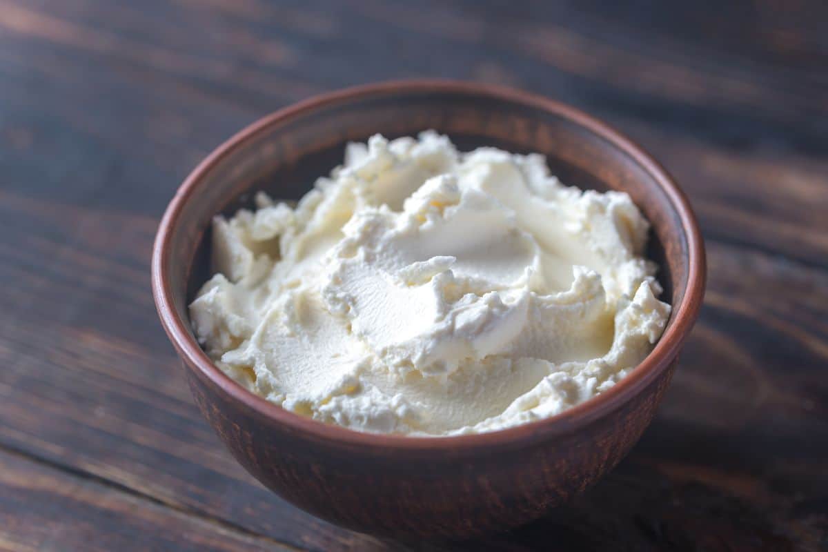 2 cups of cheese in a bowl with wood board