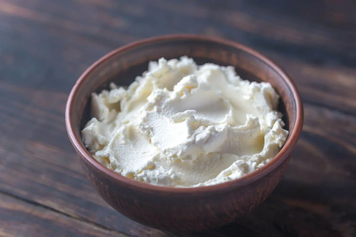 2 cups of cheese in a bowl with wood board