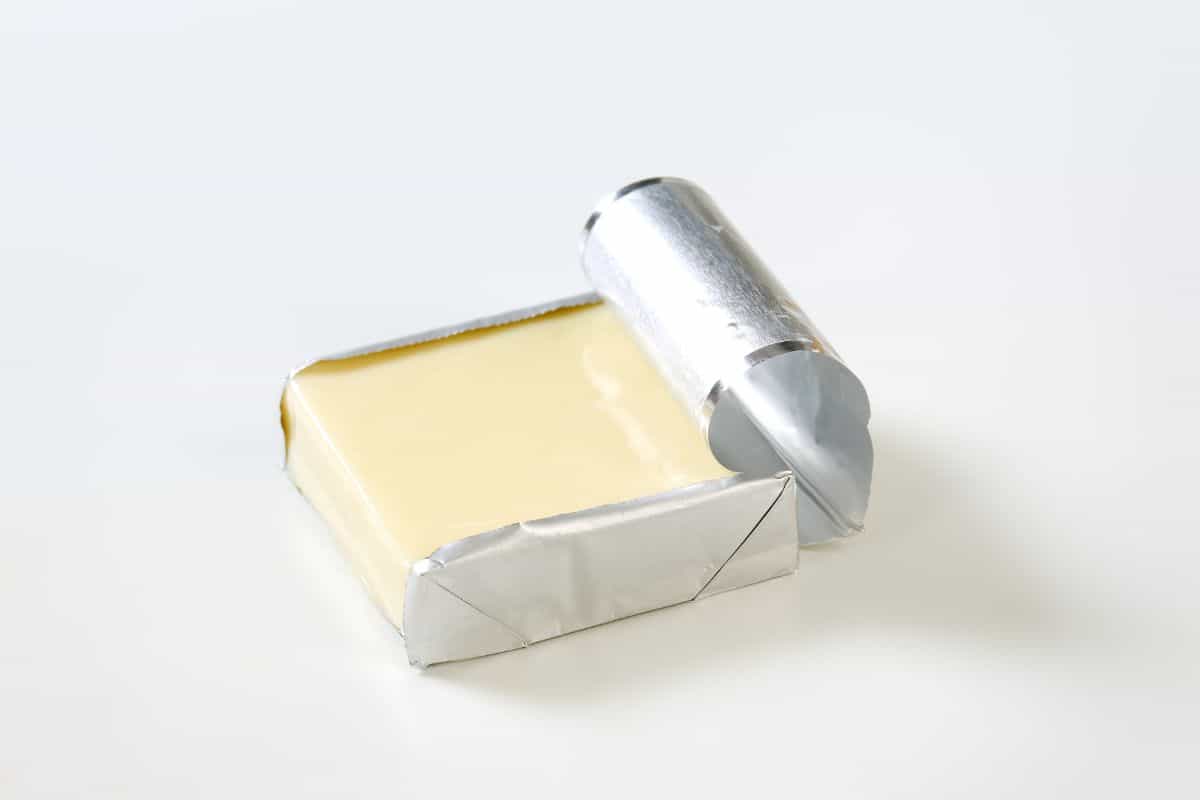 block of cream cheese in foil wrapper with it torn open