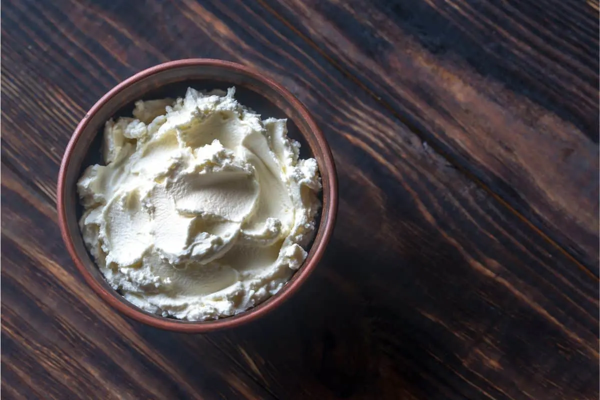 small bowl on a wood board with white cream