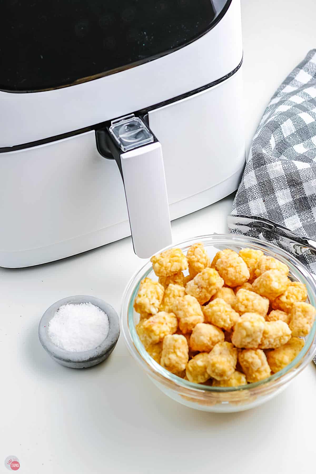 frozen tots in a bowl next to air fryer