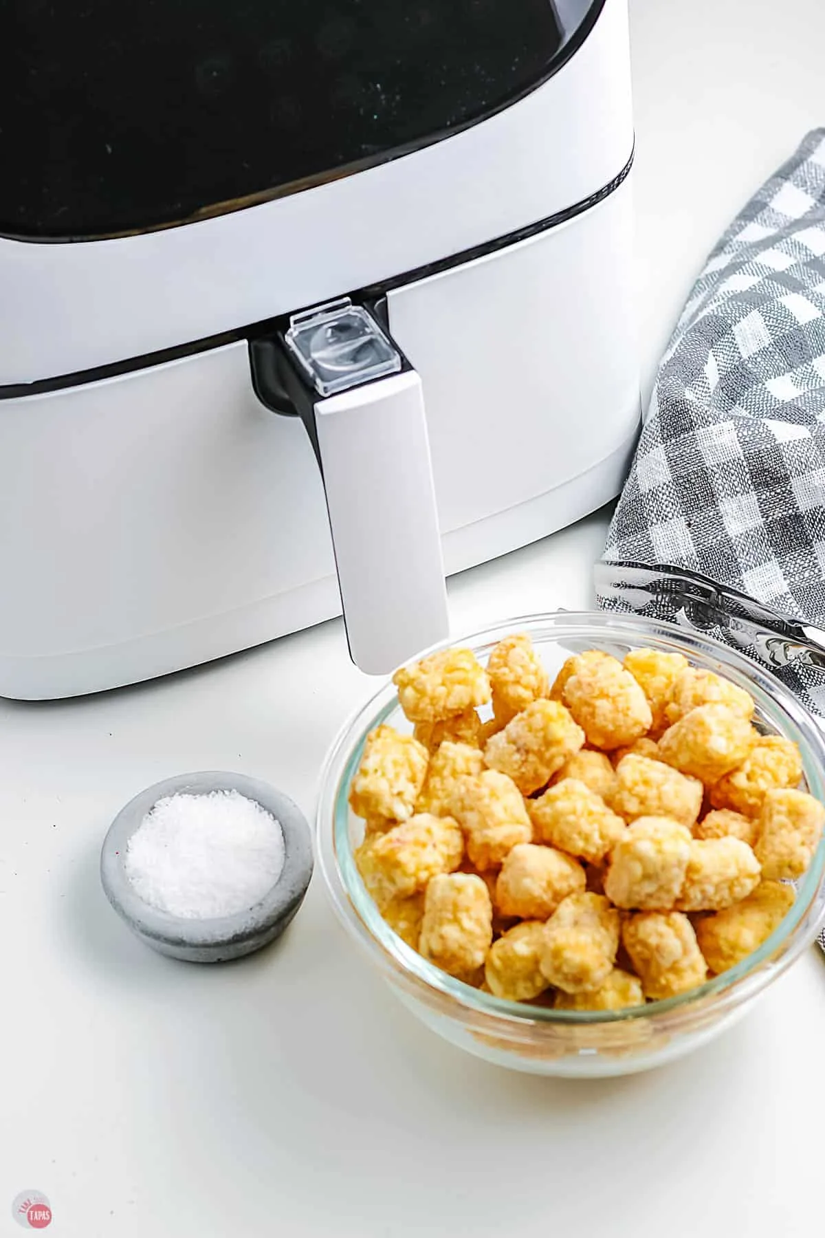 frozen tots in a bowl next to air fryer