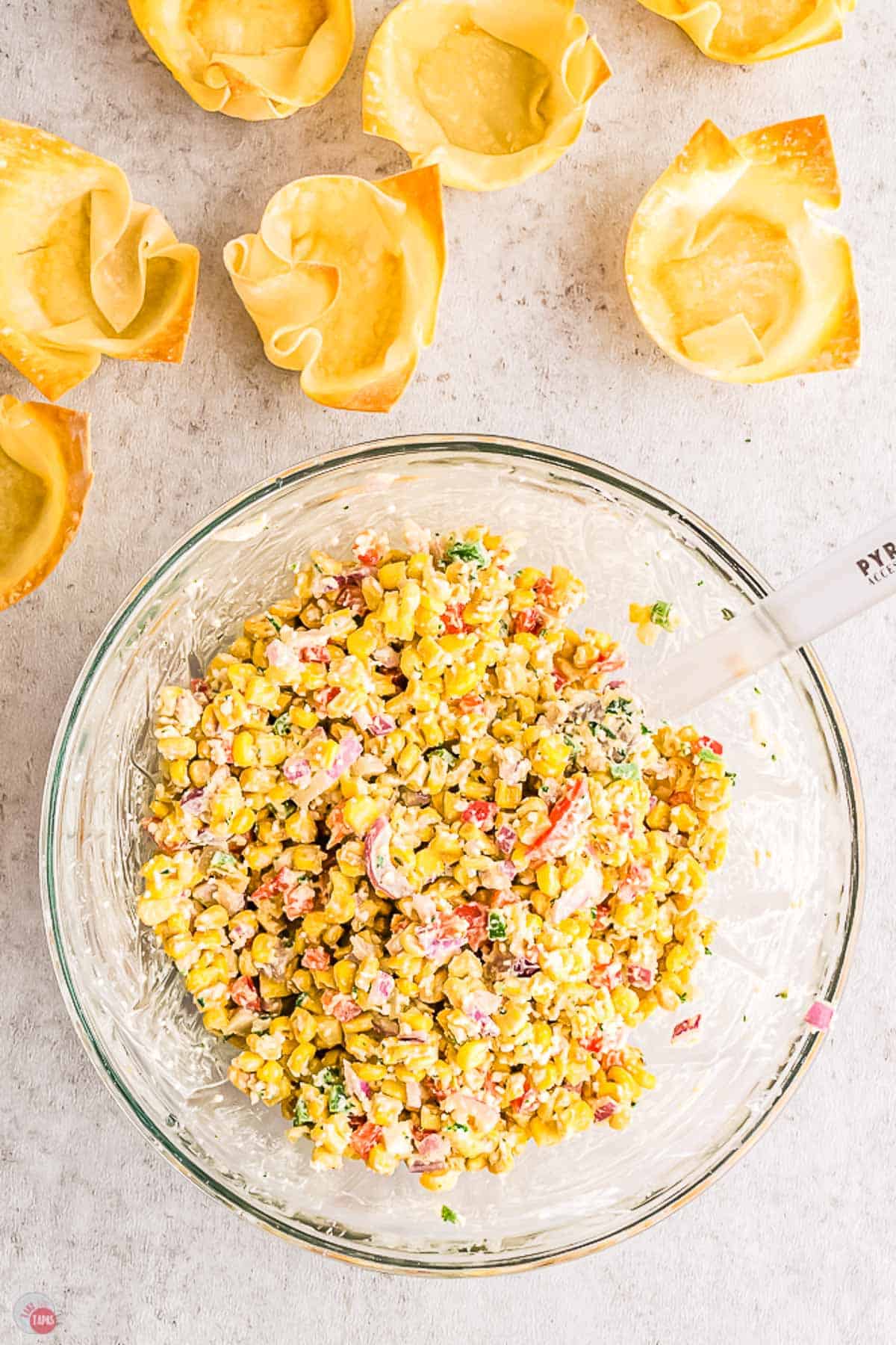 corn and dressing being mixed together in a clear bowl