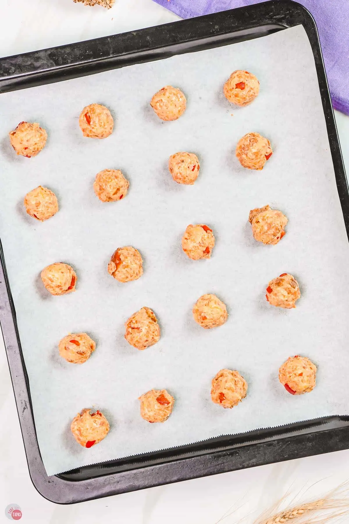 unbaked pimento cheese sausage balls on a baking sheet lined with parchment paper