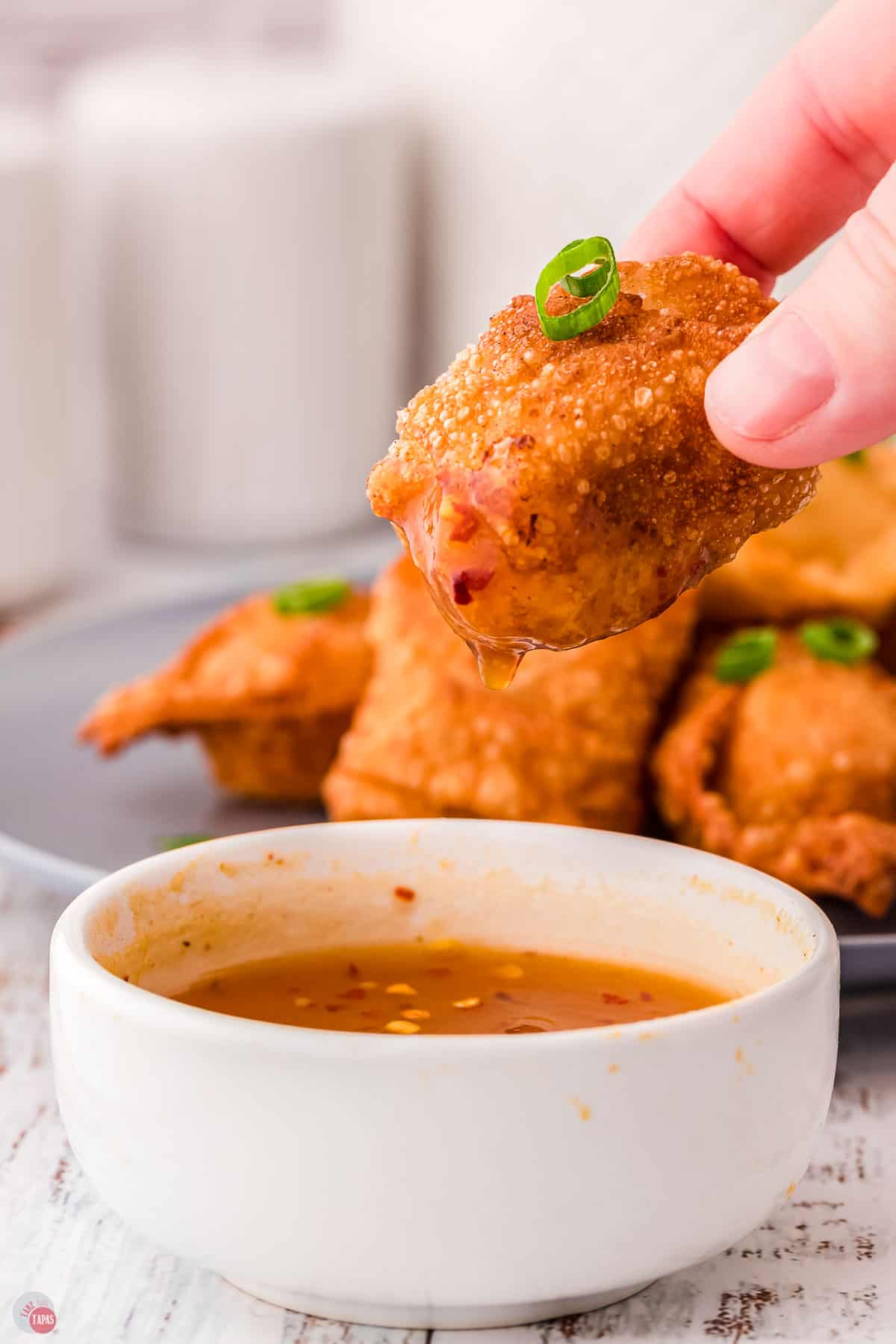 hand dipping a shrimp rangoon in sauce