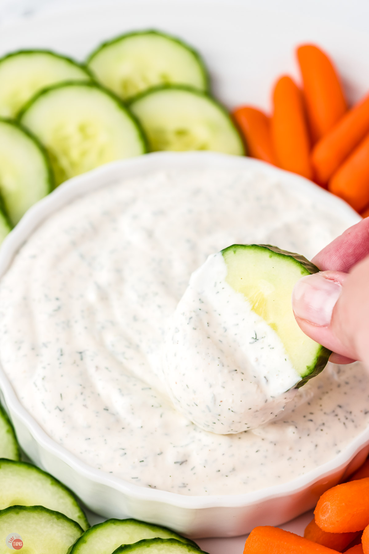creamy dip in a white bowl with carrots and cucumbers